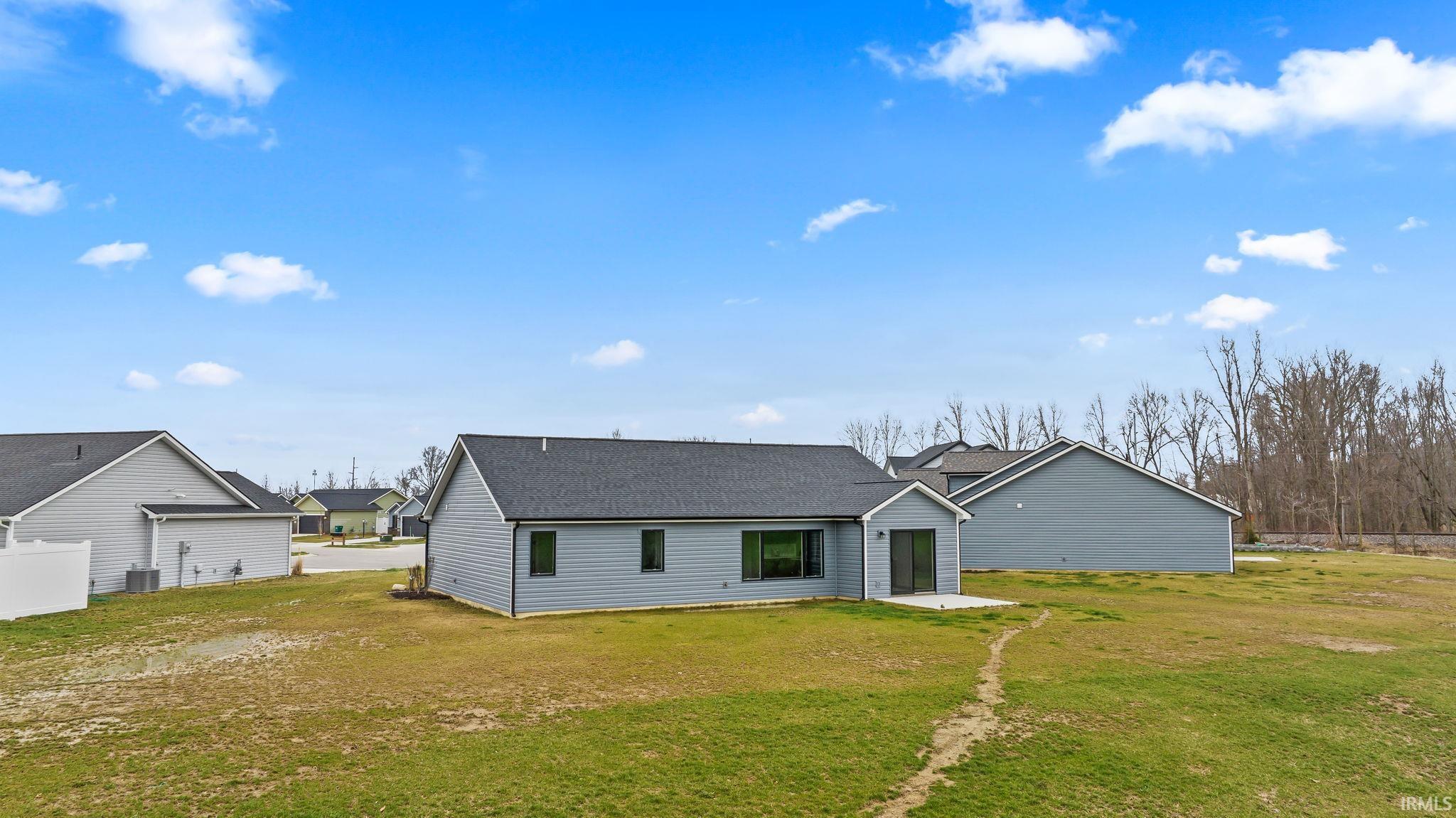 Back of property featuring a shingled roof, a yard, and a patio area