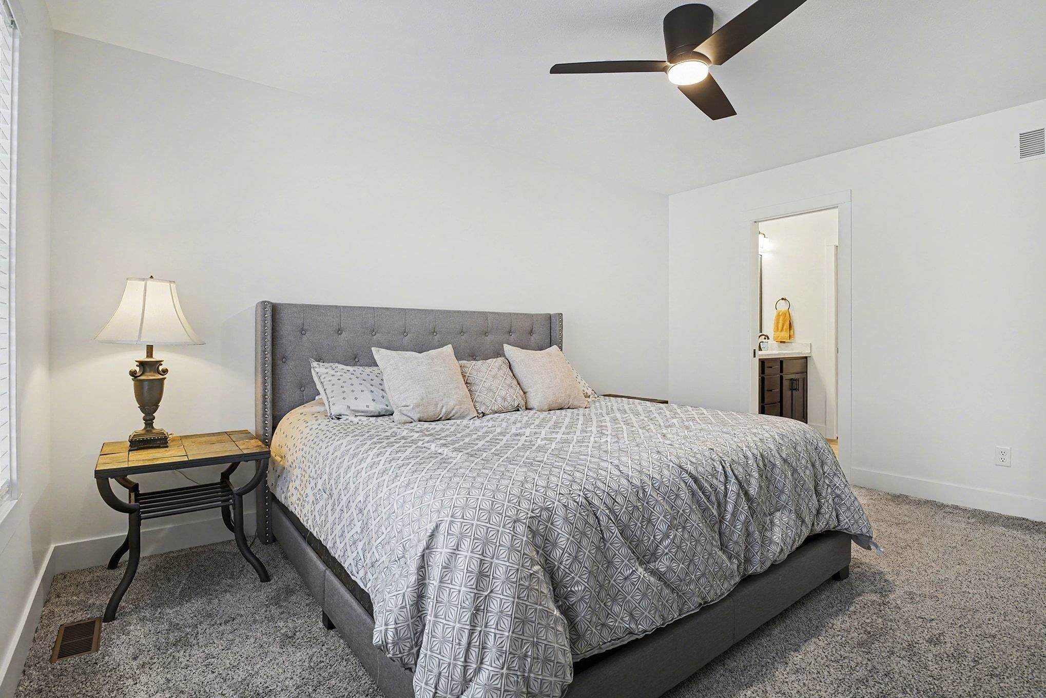 Carpeted bedroom featuring ceiling fan and ensuite bathroom
