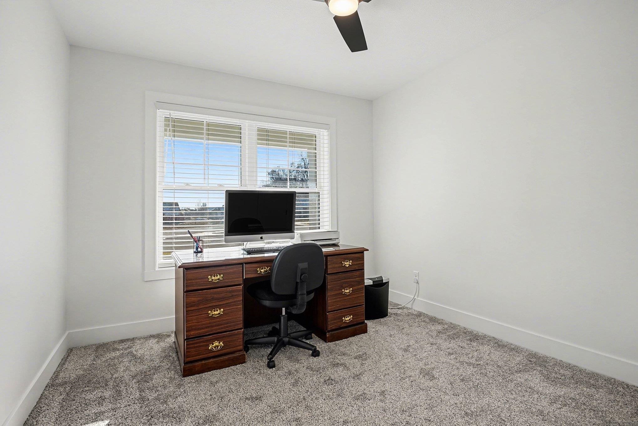 Office with light carpet and ceiling fan