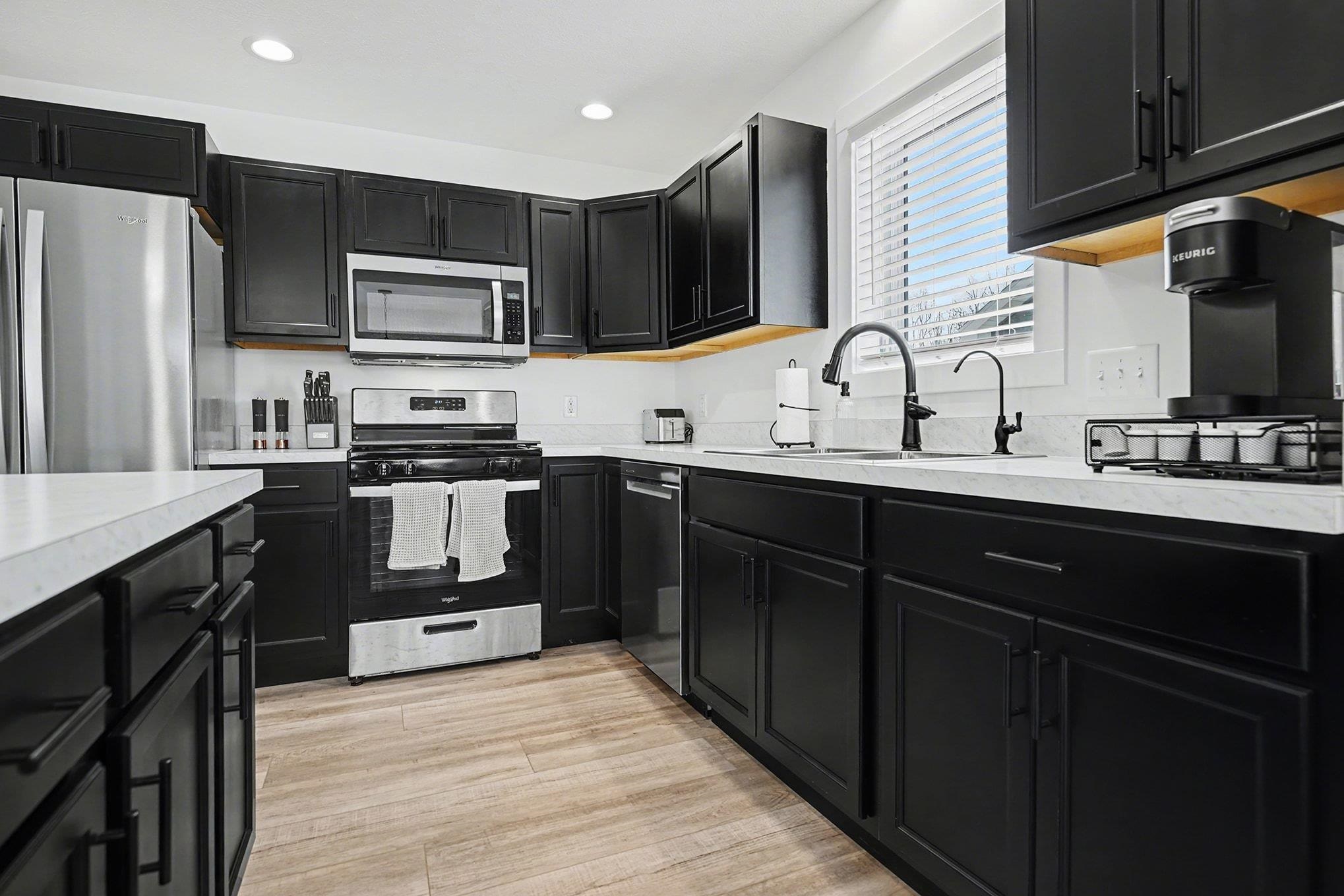 Kitchen featuring dark cabinets, light countertops, stainless steel appliances, recessed lighting, and light wood-type flooring