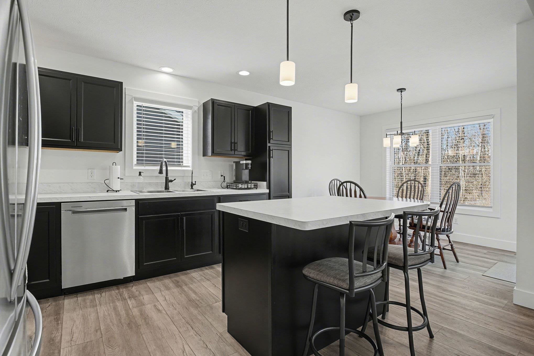 Kitchen with dark cabinets, a kitchen breakfast bar, stainless steel appliances, light countertops, and recessed lighting