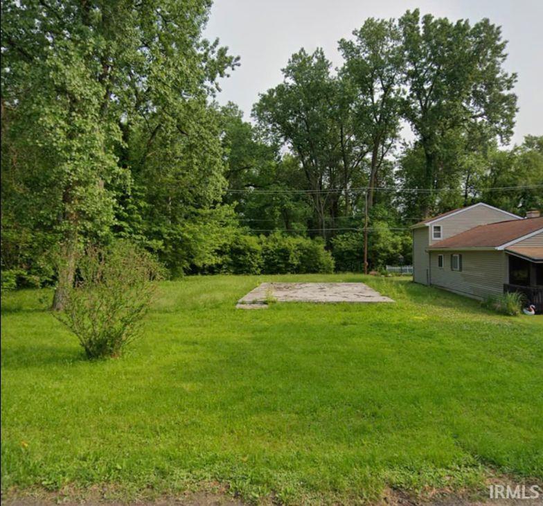 View of grassy yard featuring view of scattered trees