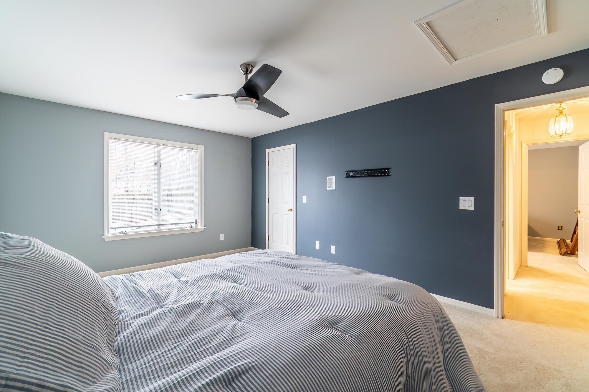 Carpeted bedroom with attic access and ceiling fan