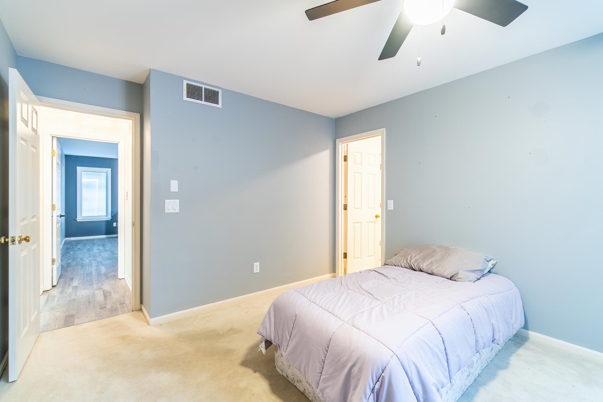Carpeted bedroom with ceiling fan and baseboards