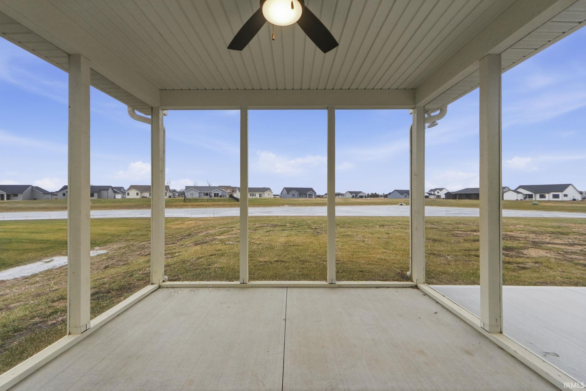 Unfurnished sunroom featuring ceiling fan, a residential view, and healthy amount of natural light