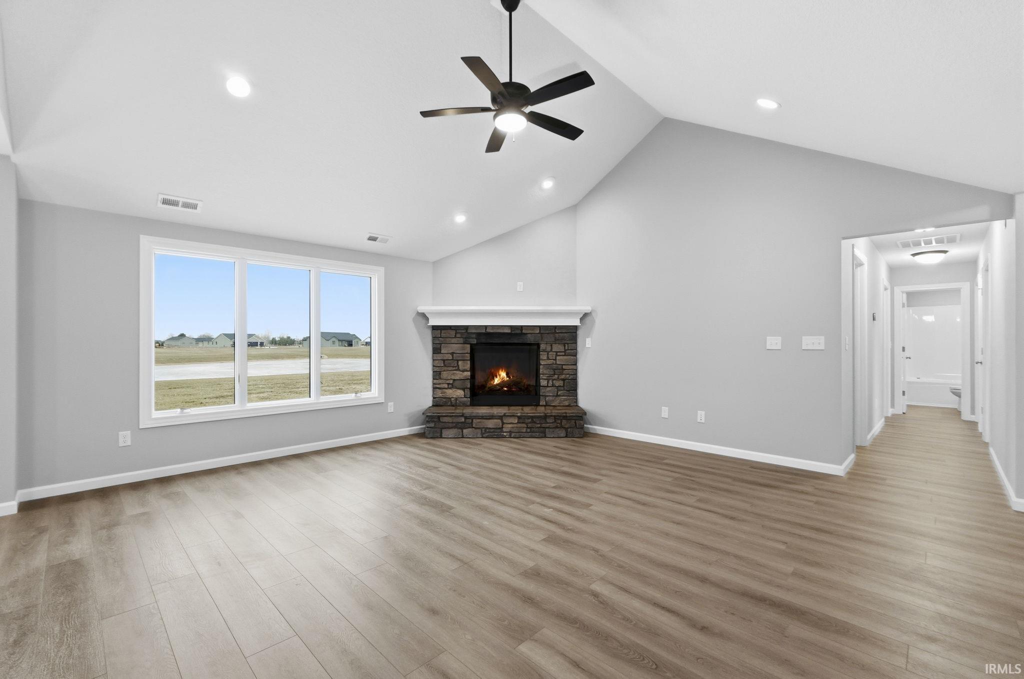 Unfurnished living room with light wood-type flooring, a fireplace, ceiling fan, and high vaulted ceiling