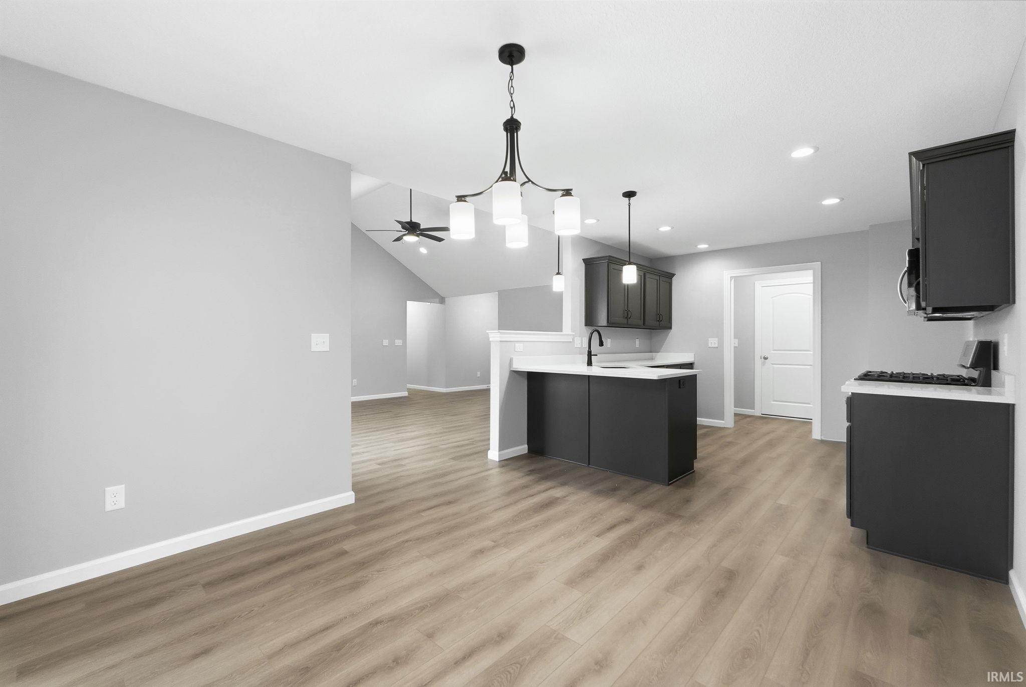 Kitchen with a peninsula, open floor plan, a ceiling fan, decorative light fixtures, and dark cabinetry