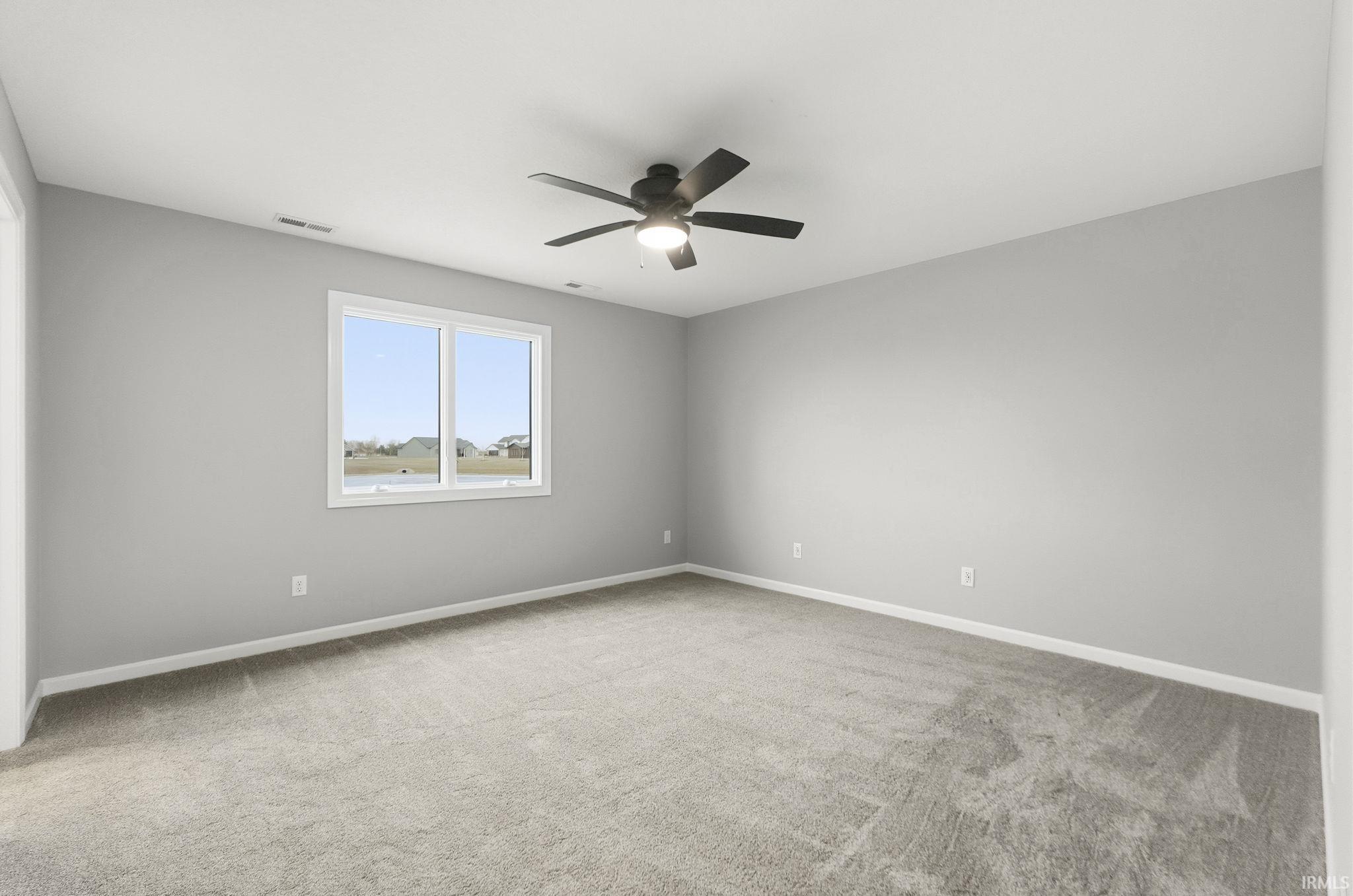 Spare room featuring light carpet and ceiling fan