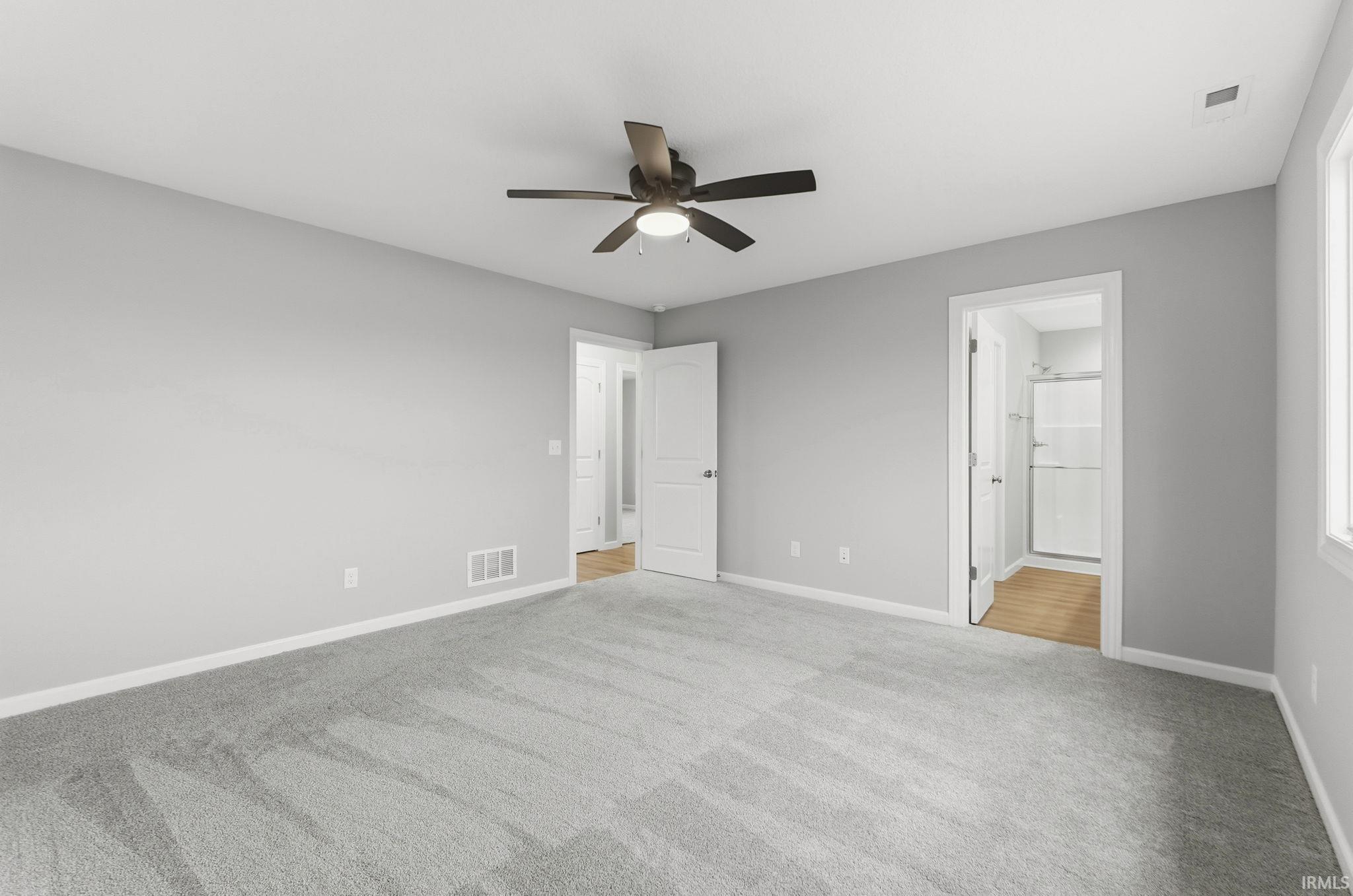 Unfurnished bedroom with light carpet, ceiling fan, and ensuite bath