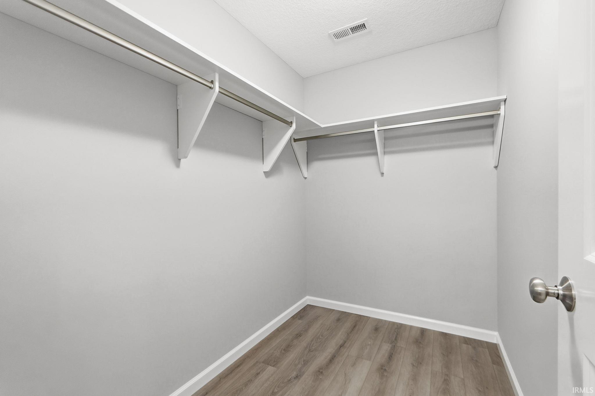 Walk in closet with light wood finished floors