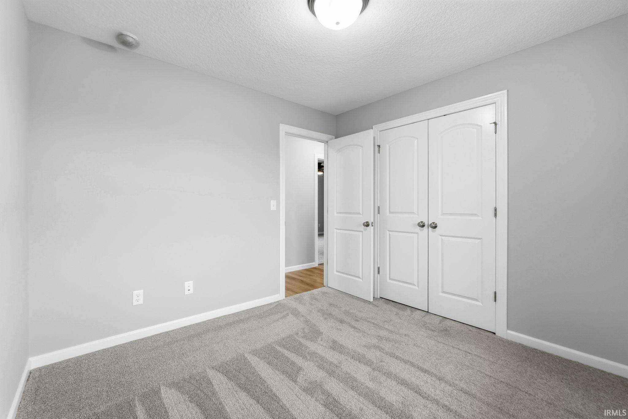 Unfurnished bedroom with a textured ceiling, a closet, and carpet floors