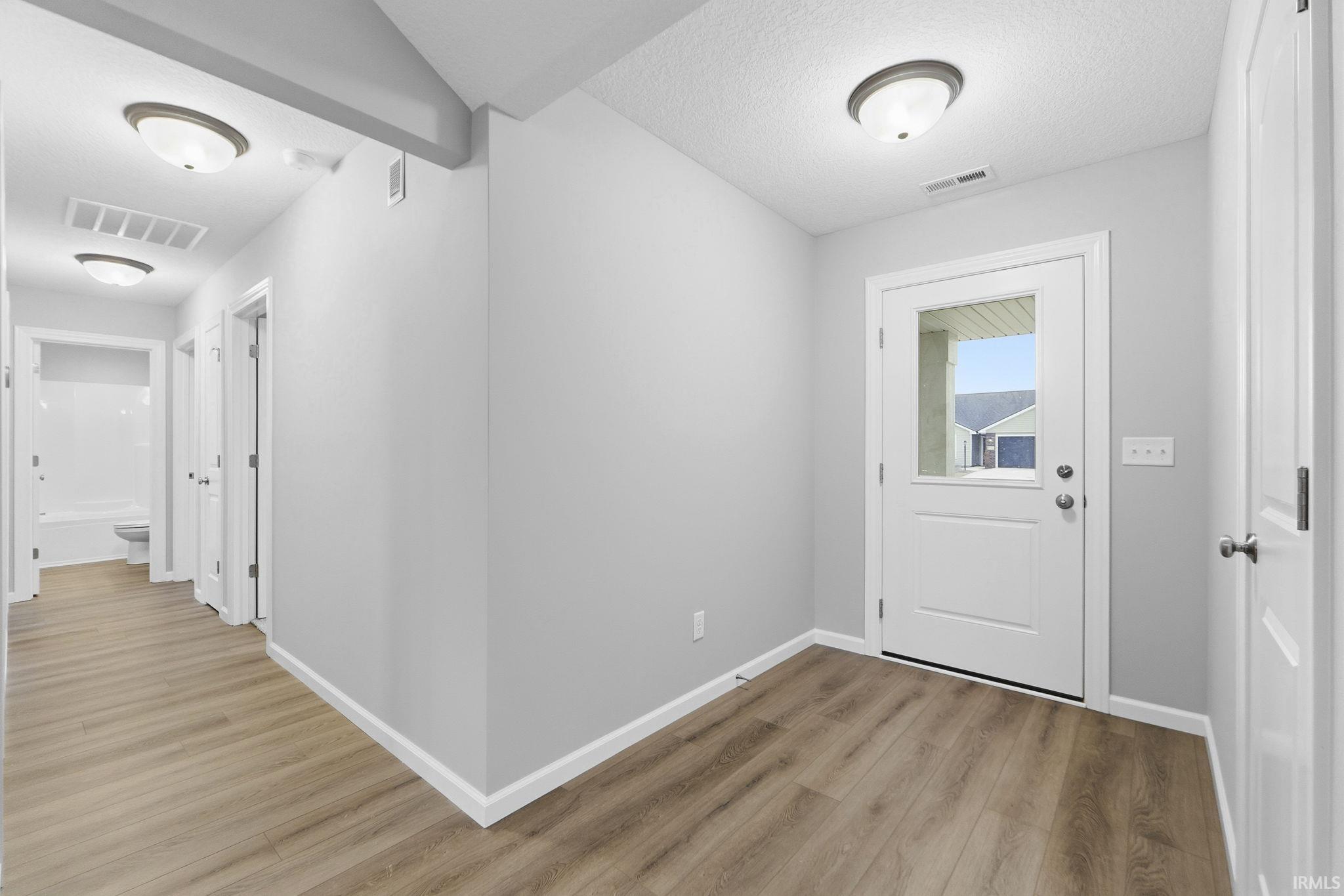 Hallway with light wood finished floors and a textured ceiling