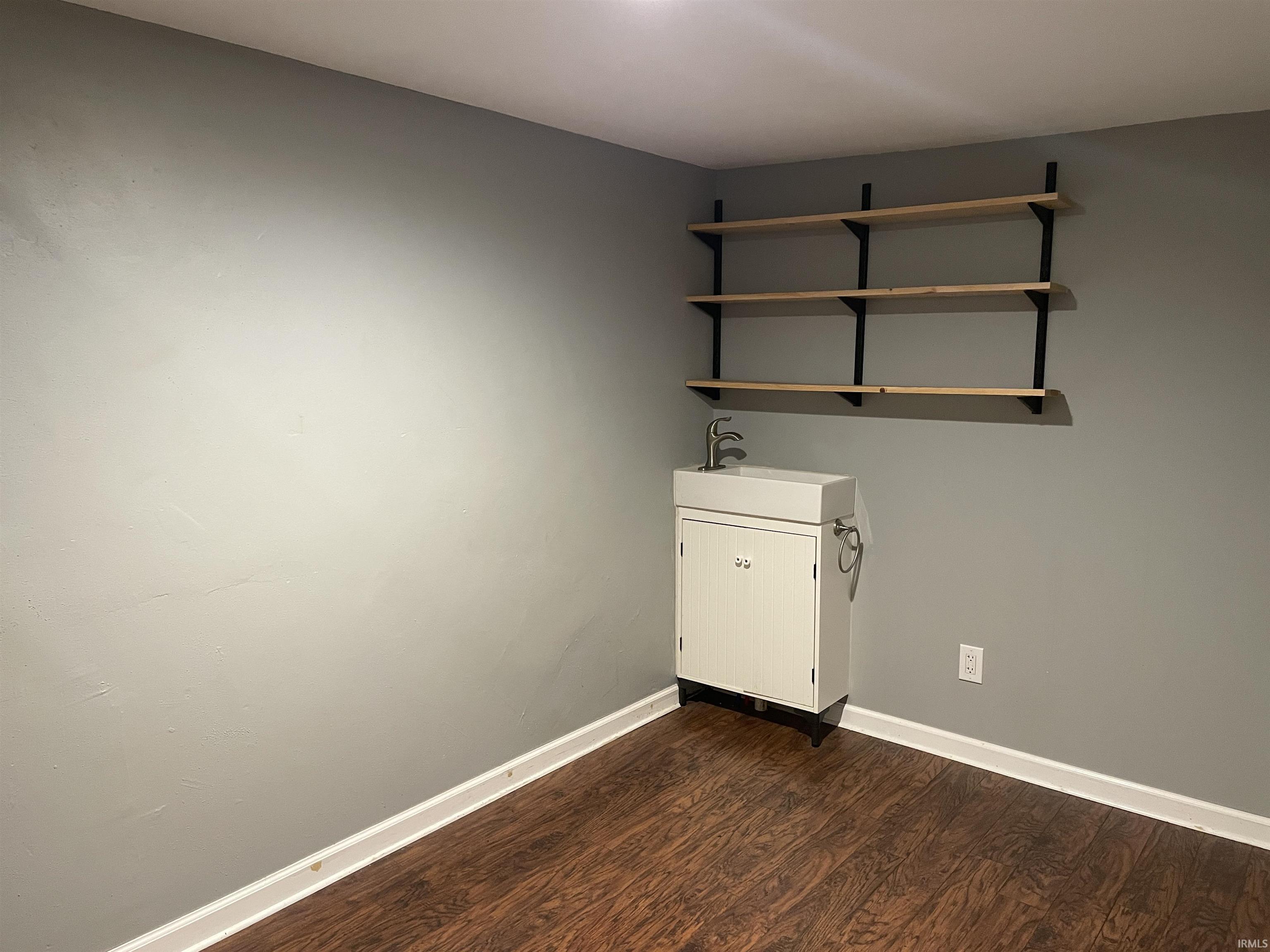 Spare room with baseboards and dark wood finished floors