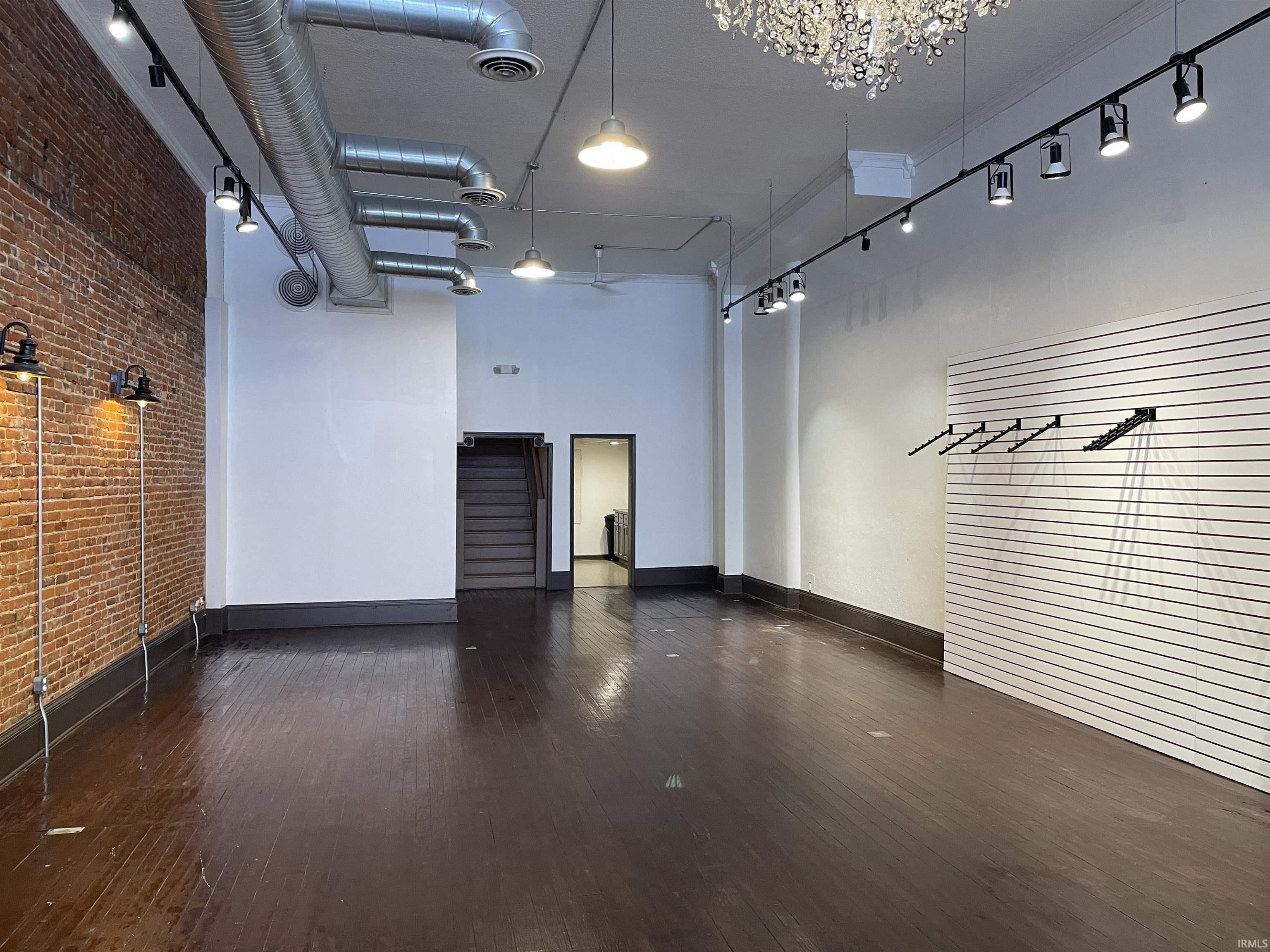 Misc room with a towering ceiling and brick wall