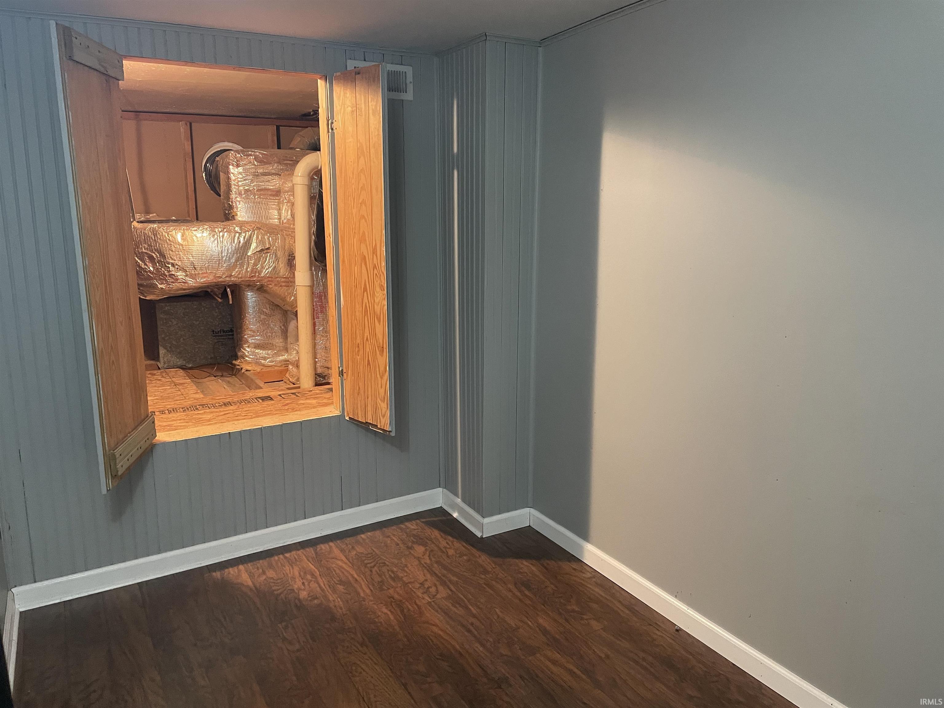Unfurnished room featuring dark wood-type flooring and wood walls
