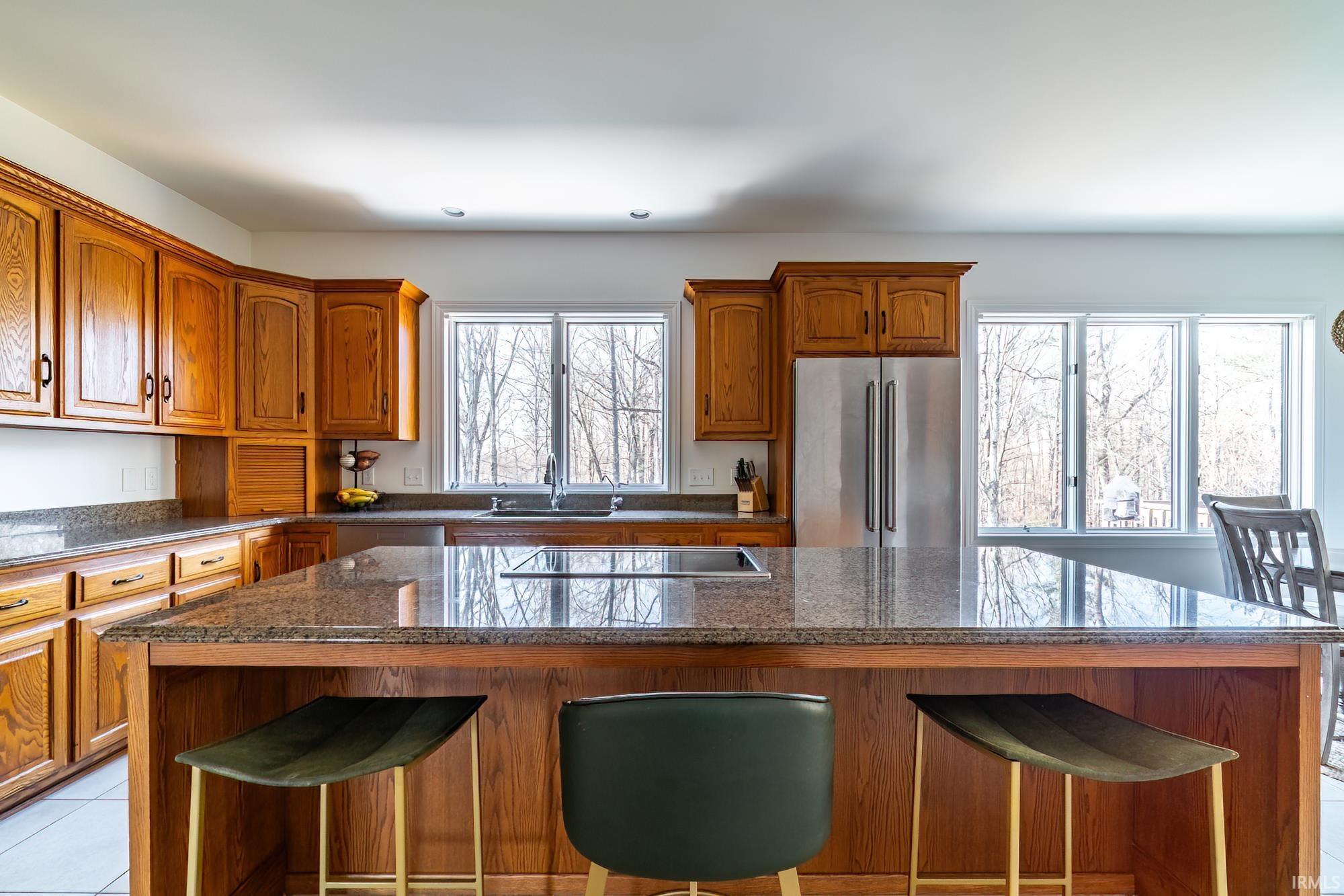 Kitchen with a kitchen bar, high end refrigerator, brown cabinetry, and a kitchen island