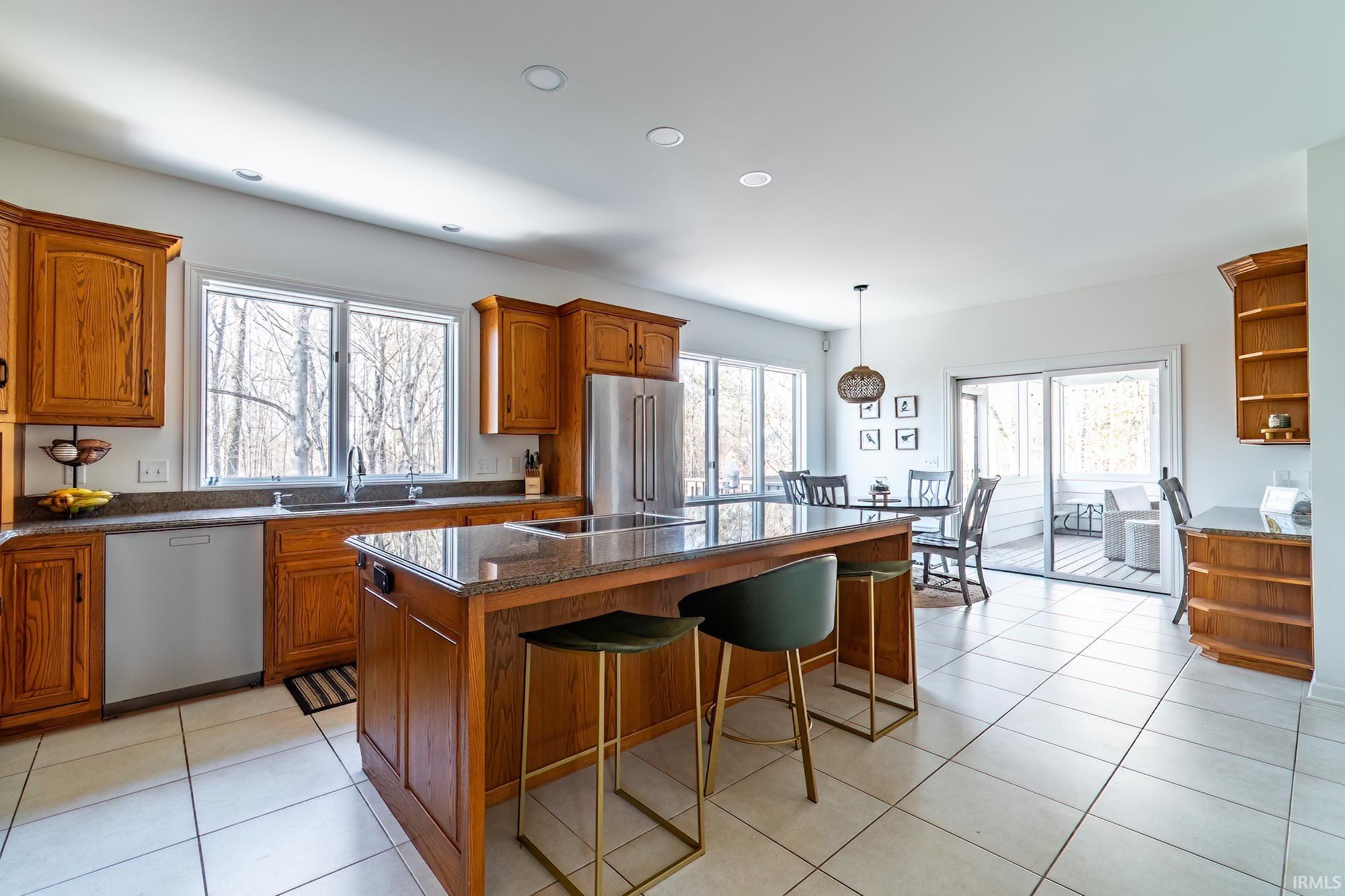 Kitchen featuring open shelves, brown cabinetry, a kitchen island, a breakfast bar area, and recessed lighting