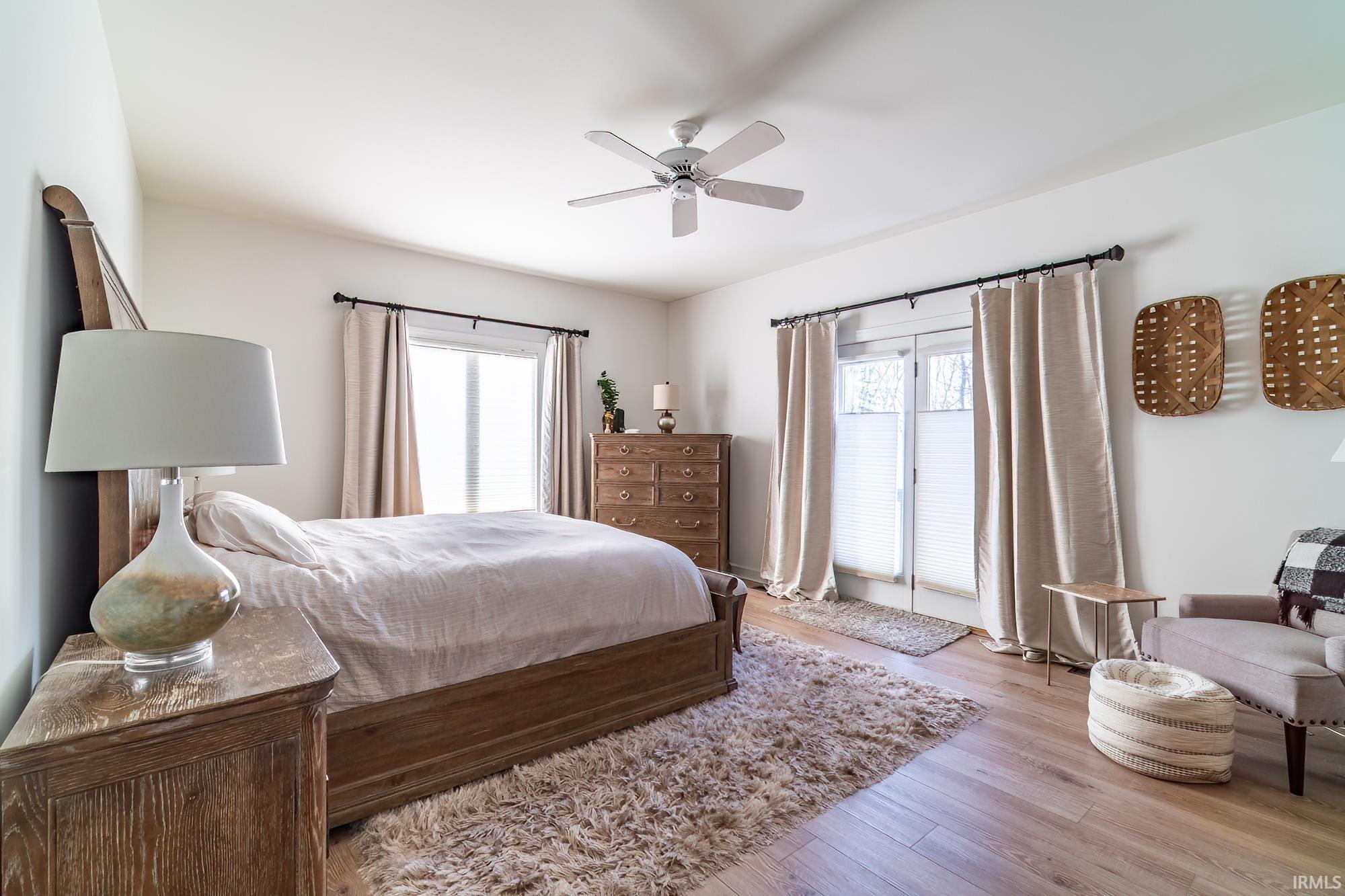 Bedroom featuring wood finished floors, a ceiling fan, multiple windows, and access to outside