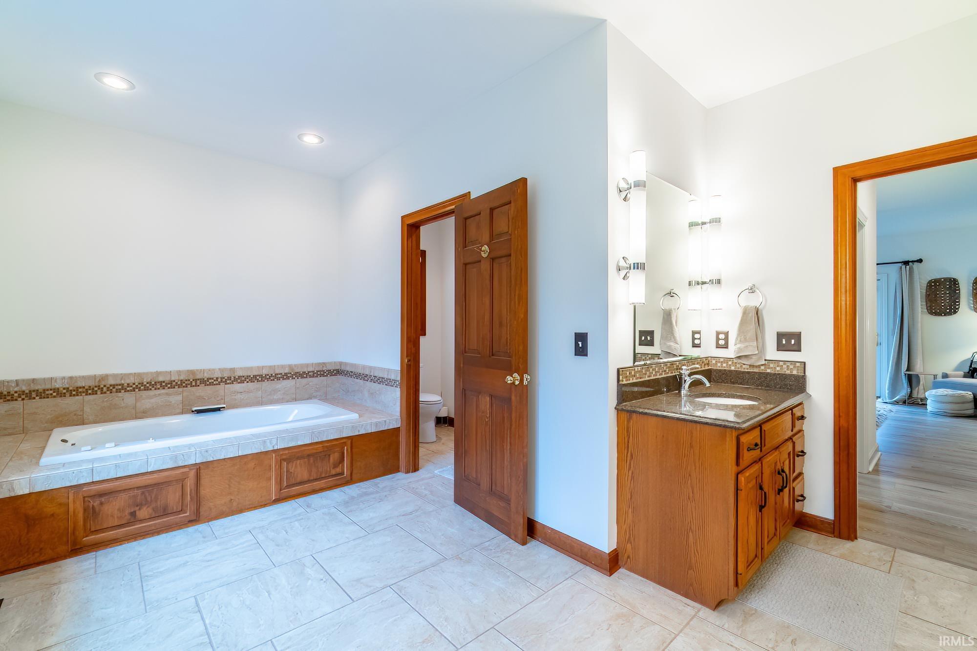 Full bathroom featuring a bath, vanity, and recessed lighting