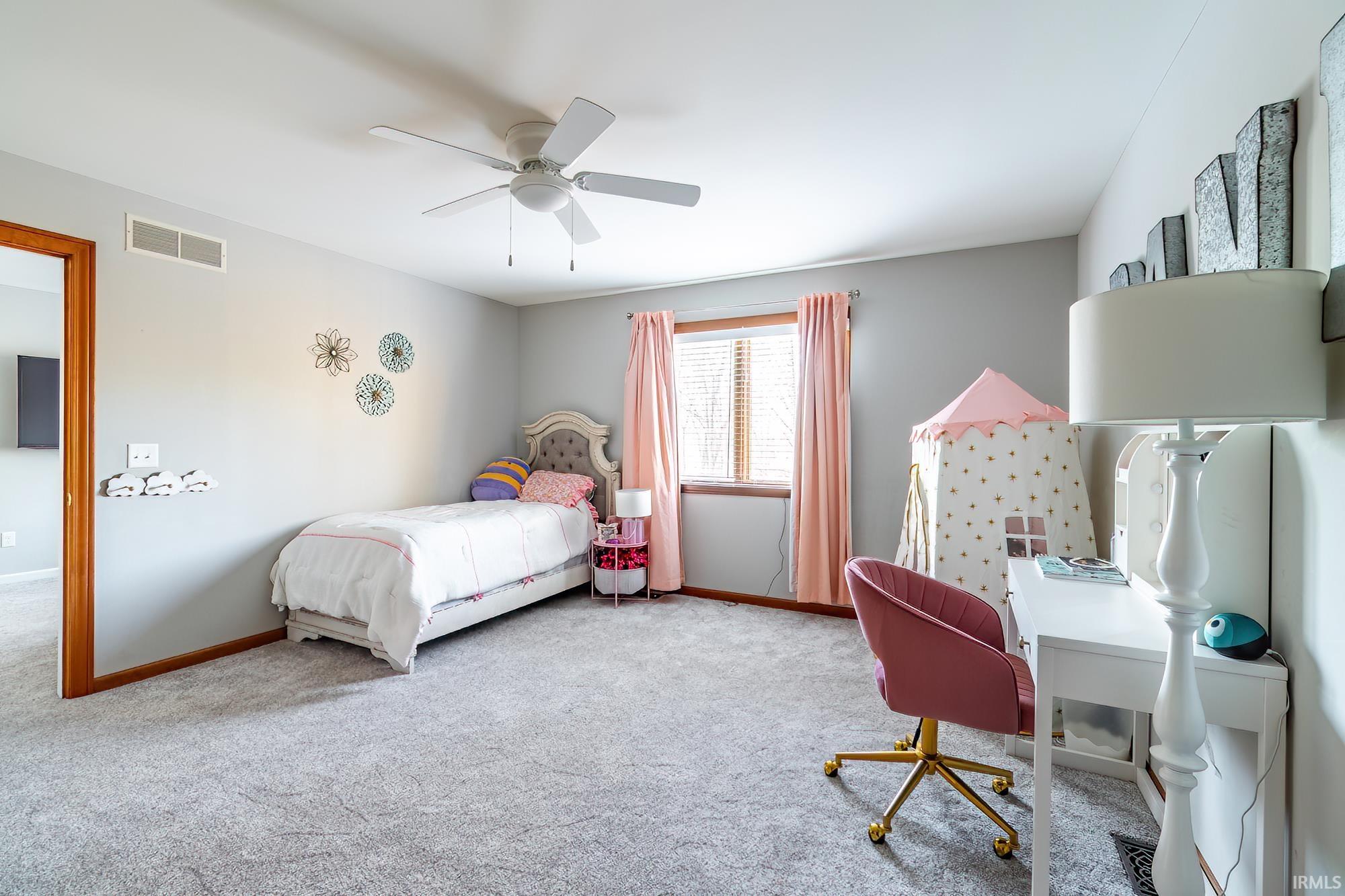 Carpeted bedroom with a ceiling fan and an office area