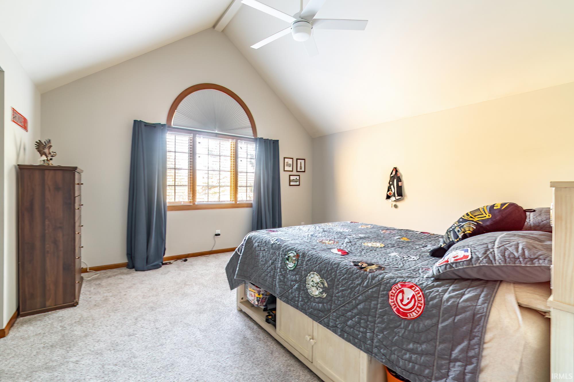 Bedroom with lofted ceiling, a ceiling fan, and light carpet