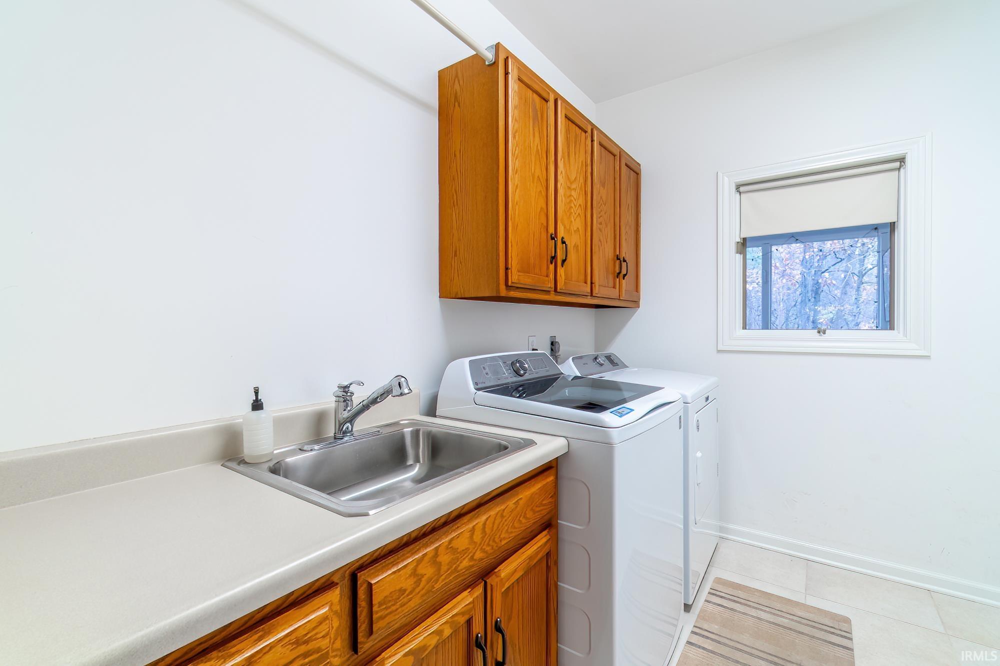 Laundry room featuring light tile patterned flooring, washer and clothes dryer, and cabinet space
