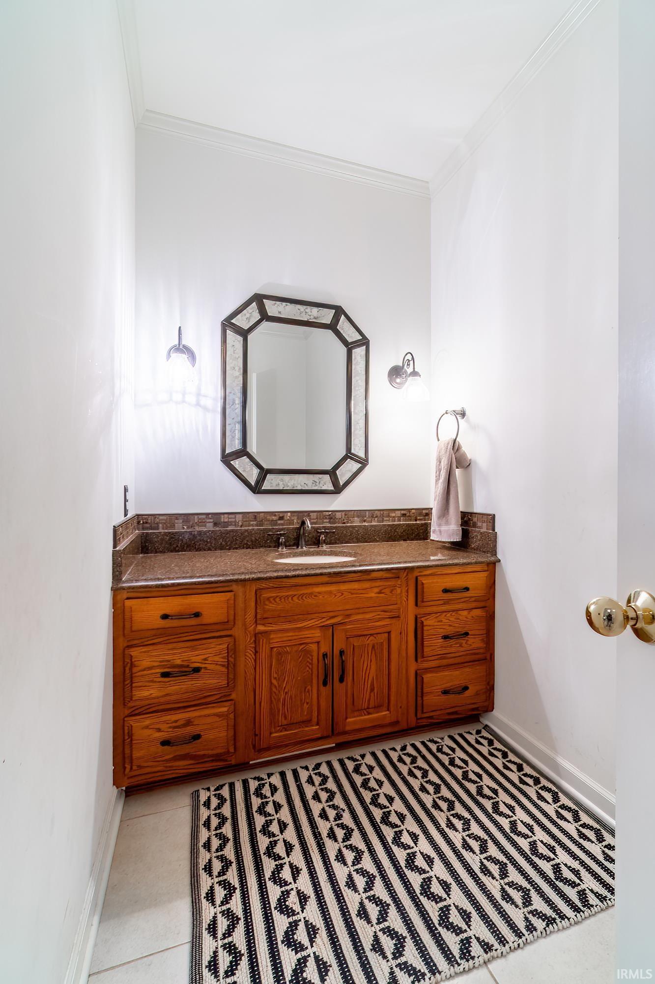 Half bath featuring vanity, ornamental molding, and light tile patterned floors