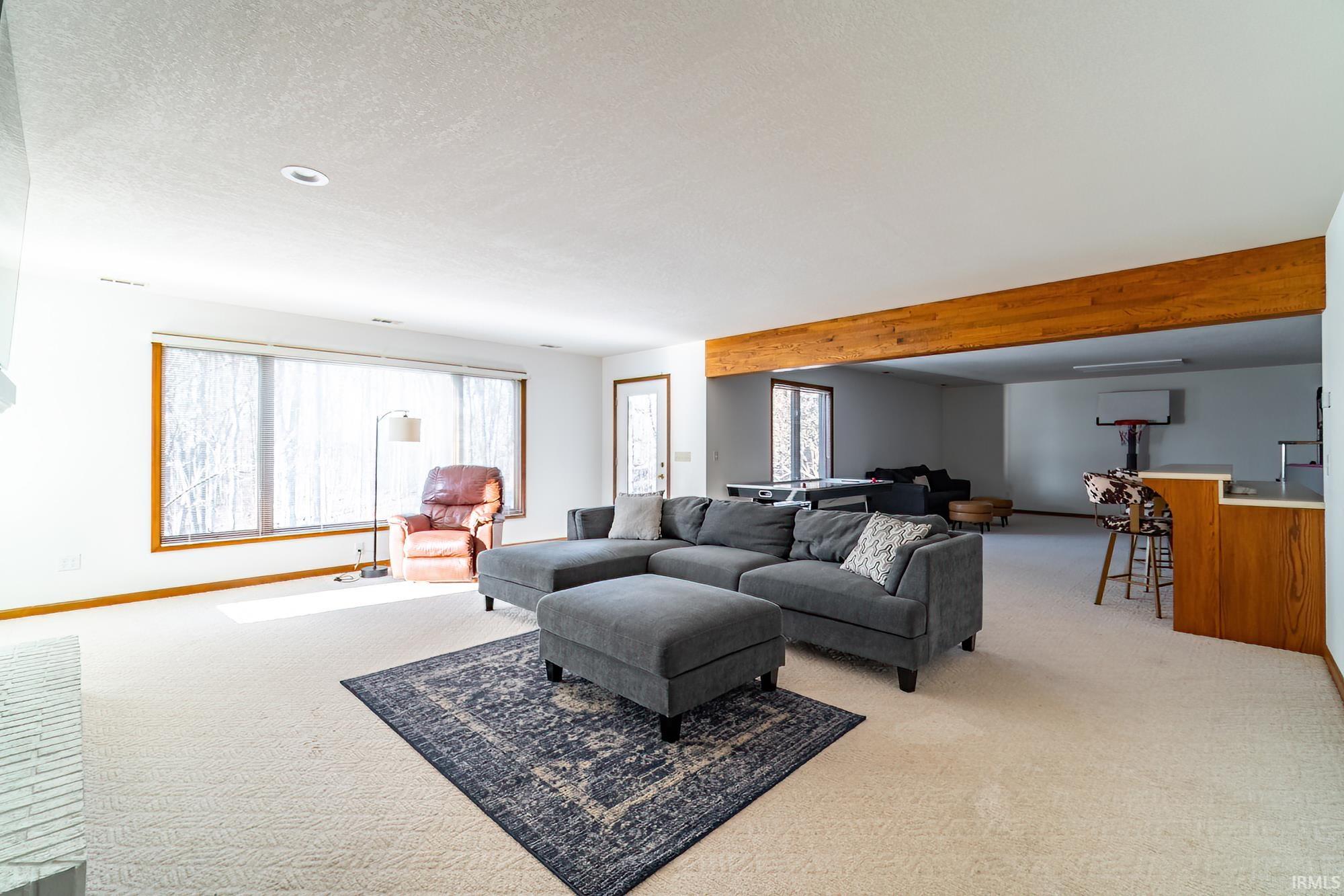 Living room featuring light colored carpet, a textured ceiling, and bar