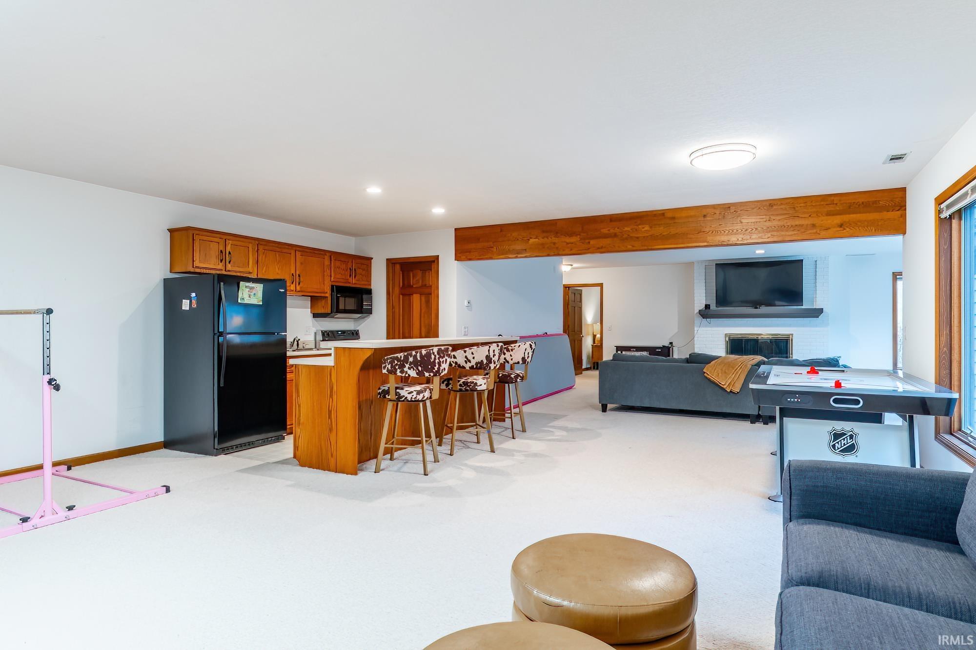 Kitchen with open floor plan, light countertops, brown cabinetry, a kitchen breakfast bar, and black appliances