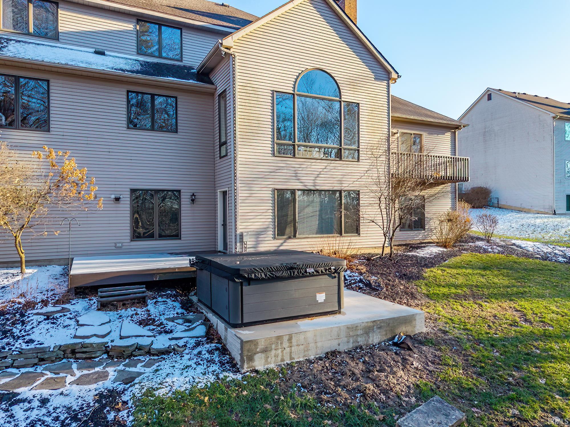 Back of property with a hot tub and a chimney