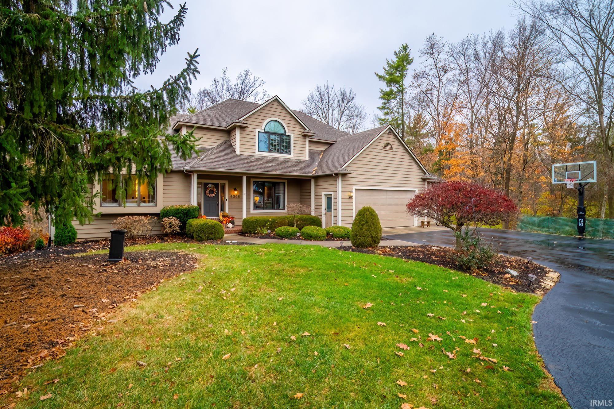 Traditional-style house with a porch, a shingled roof, driveway, and a front lawn