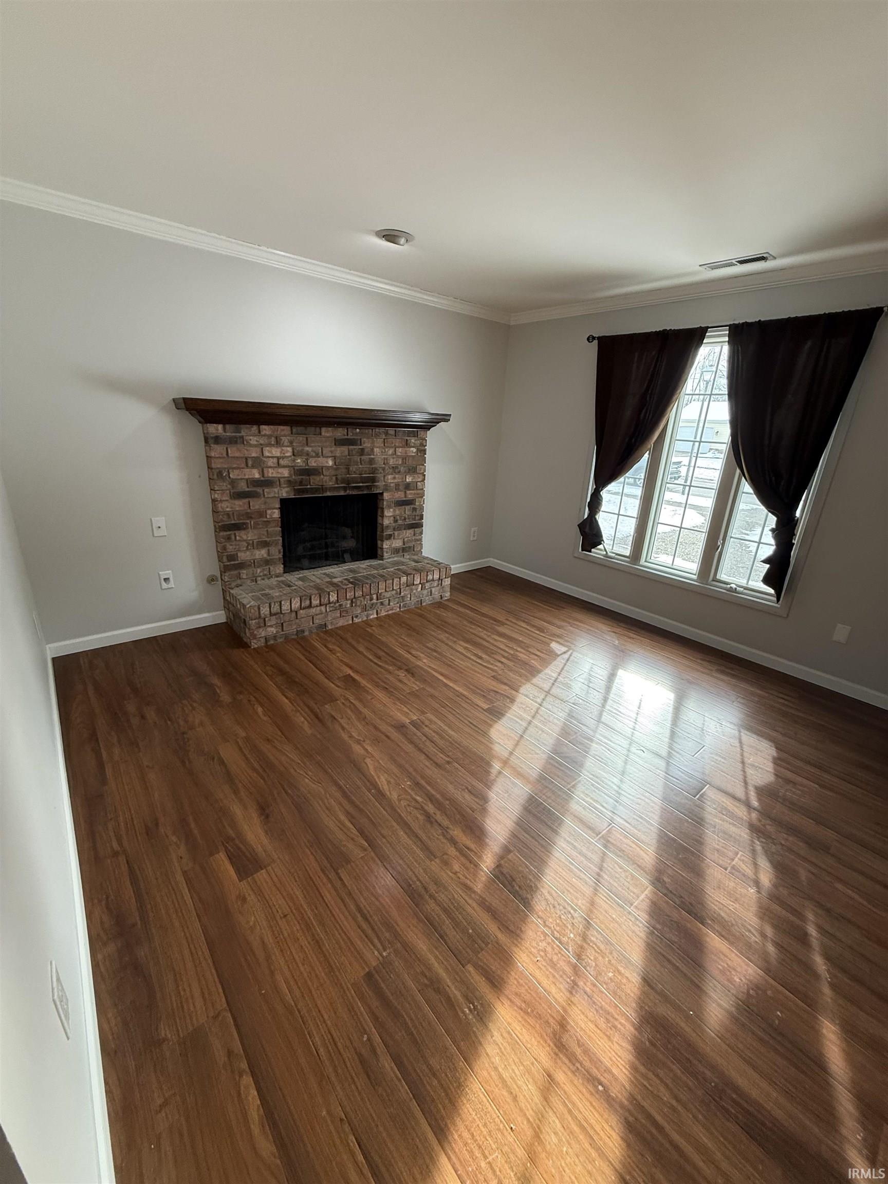 Unfurnished living room featuring a fireplace, wood finished floors, and ornamental molding