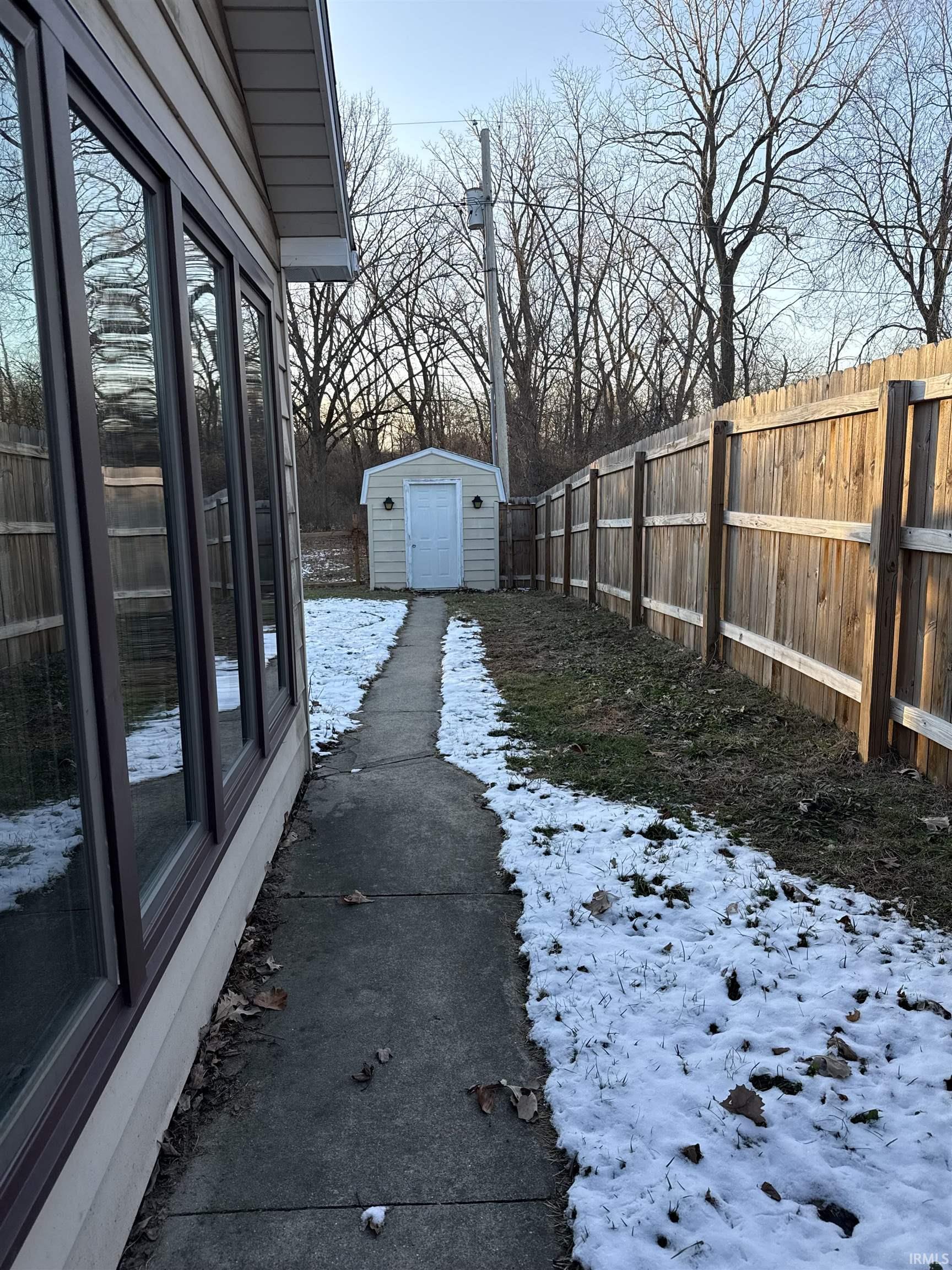 Fenced backyard featuring a shed