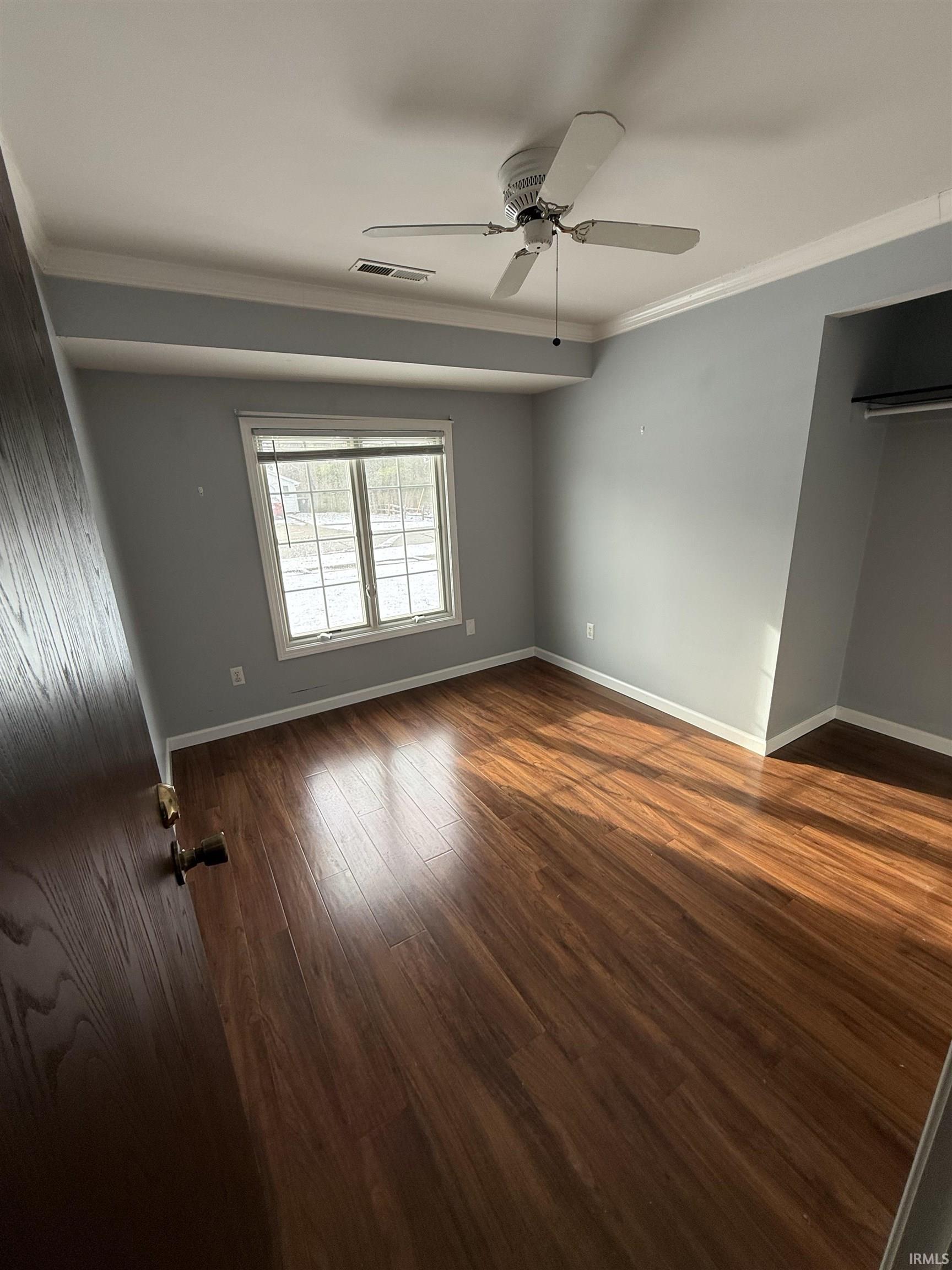 Unfurnished bedroom with ornamental molding, a ceiling fan, and dark wood-type flooring