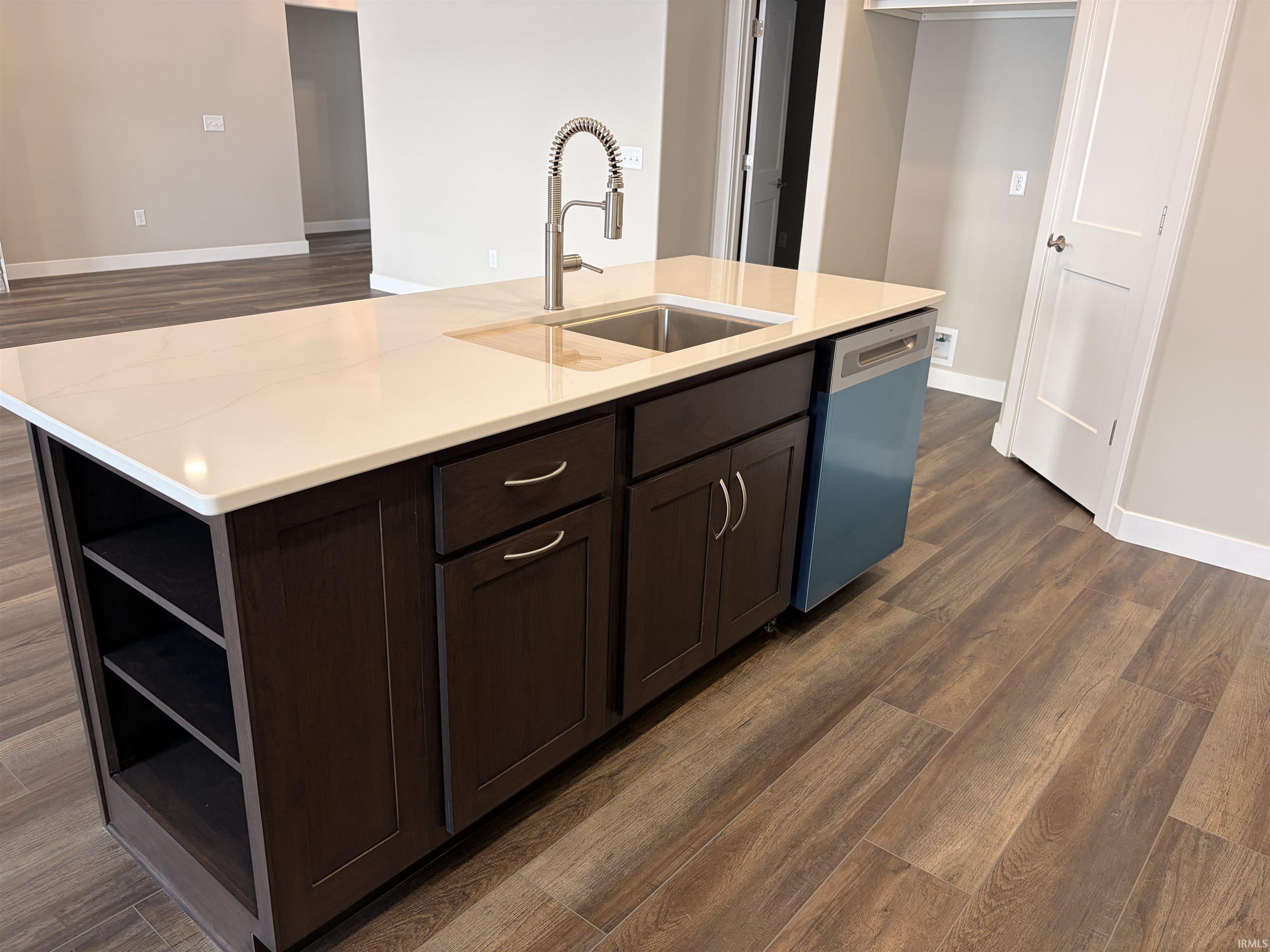 Kitchen with dark wood-style floors, a center island with sink, dishwashing machine, open shelves, and dark brown cabinets