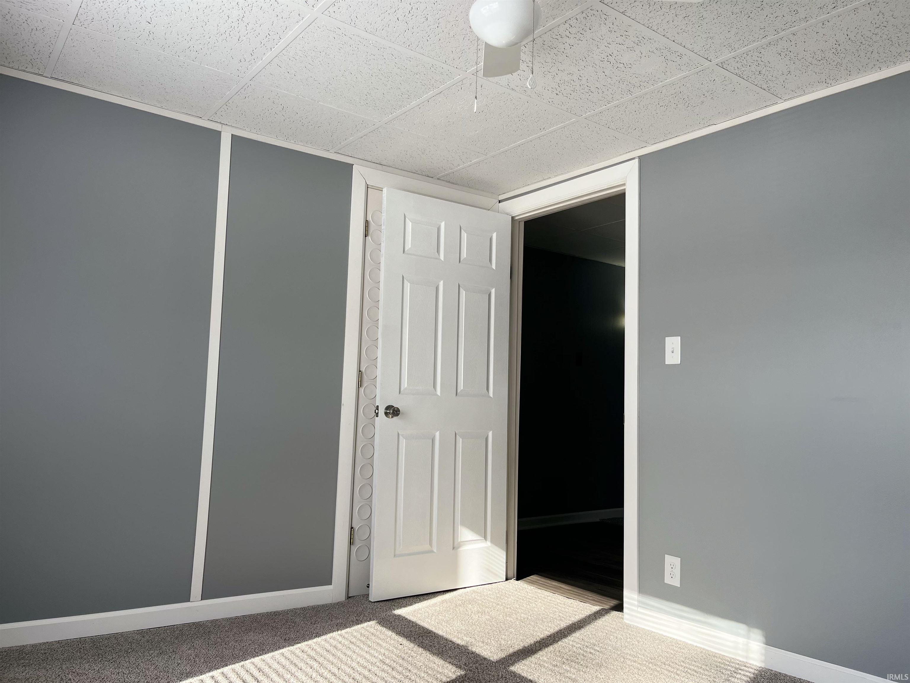 Unfurnished bedroom featuring carpet and a drop ceiling