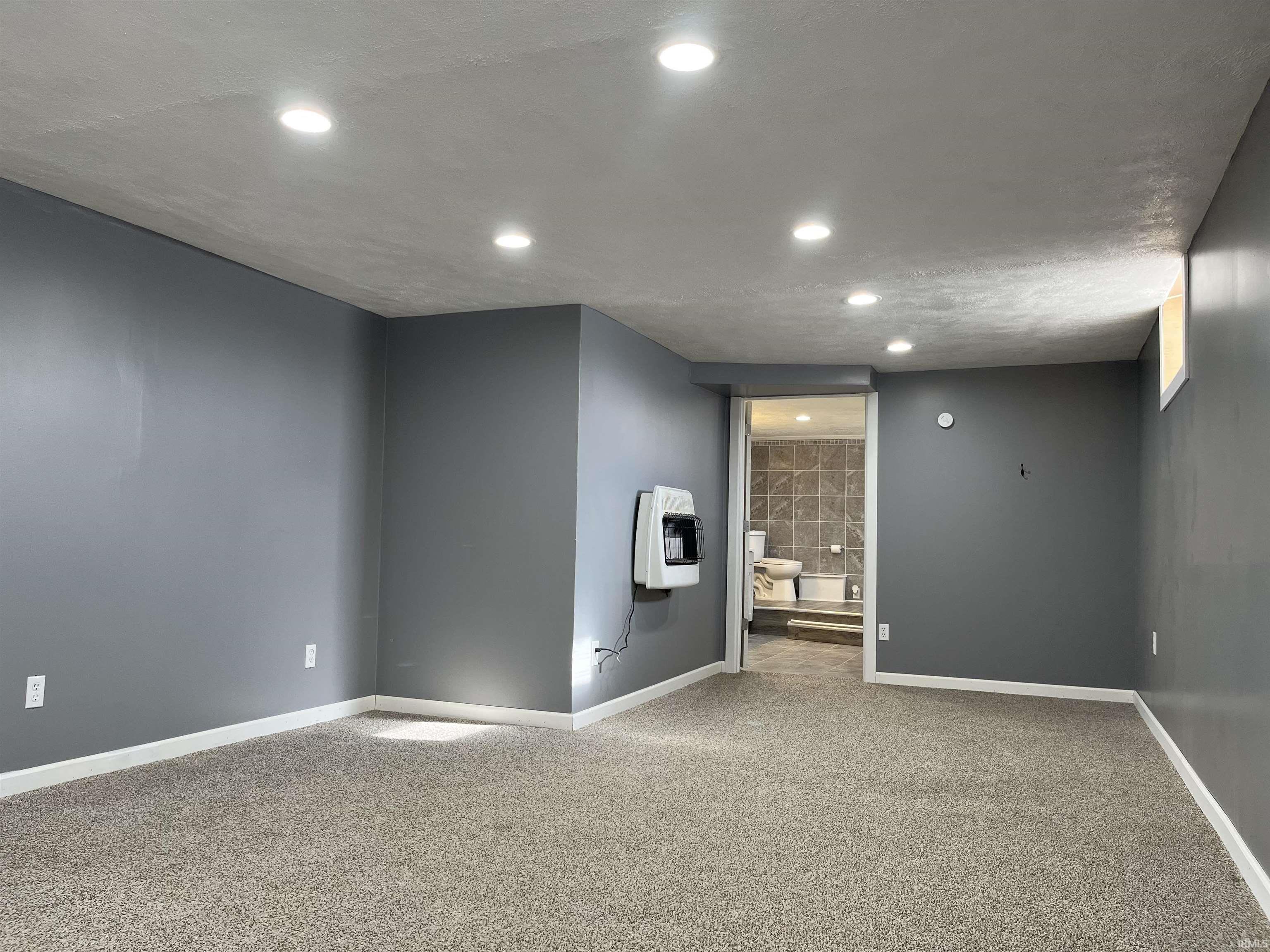 Empty room with carpet floors, recessed lighting, and heating unit