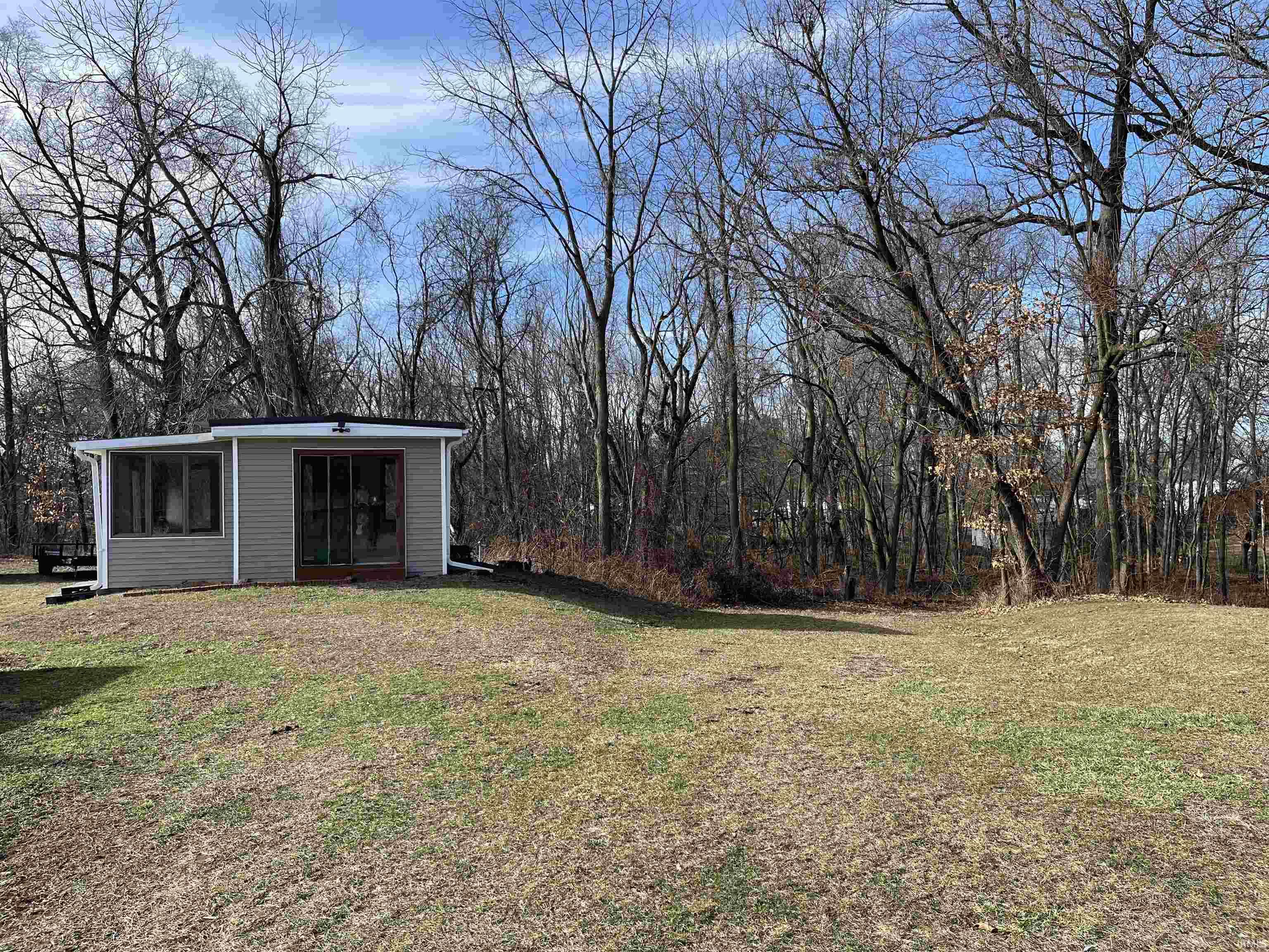 View of green lawn featuring an outbuilding with electric and a view of trees