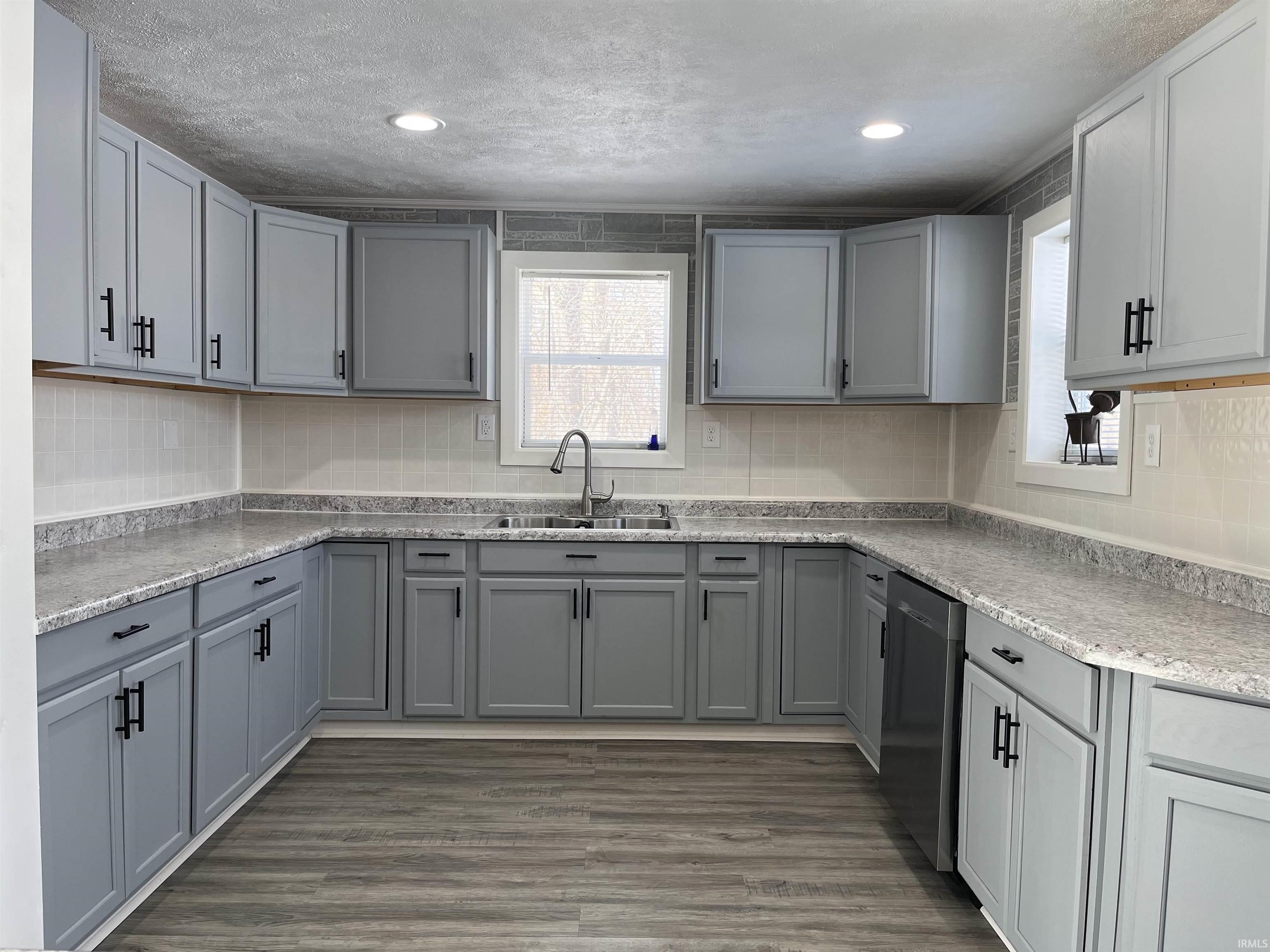 Kitchen featuring gray cabinetry, tasteful backsplash, and dishwasher