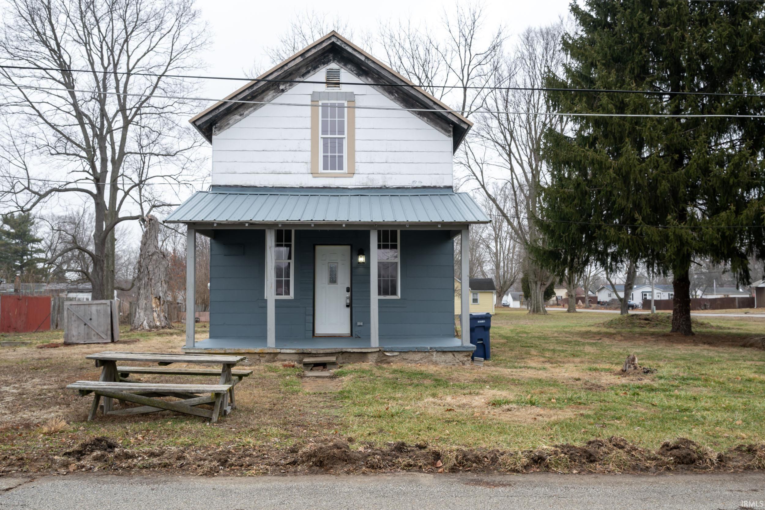 View of front of property featuring a porch, a metal roof, and a front yard