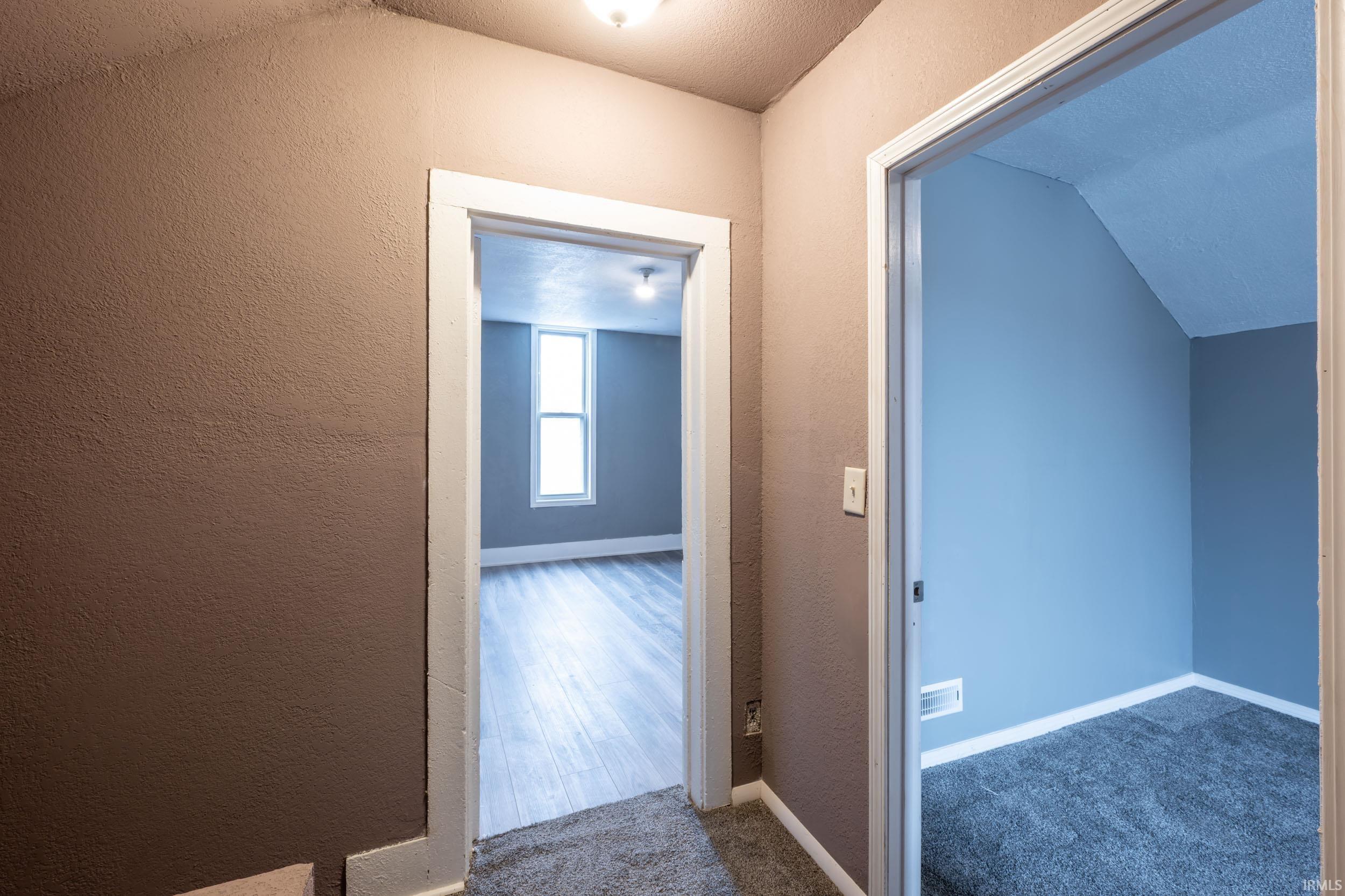 Hall with a textured wall and carpet floors