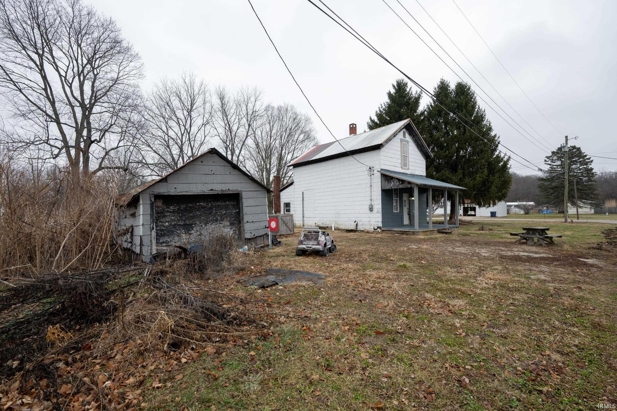 View of home's exterior with an outdoor structure, a garage, covered porch, a chimney, and a lawn