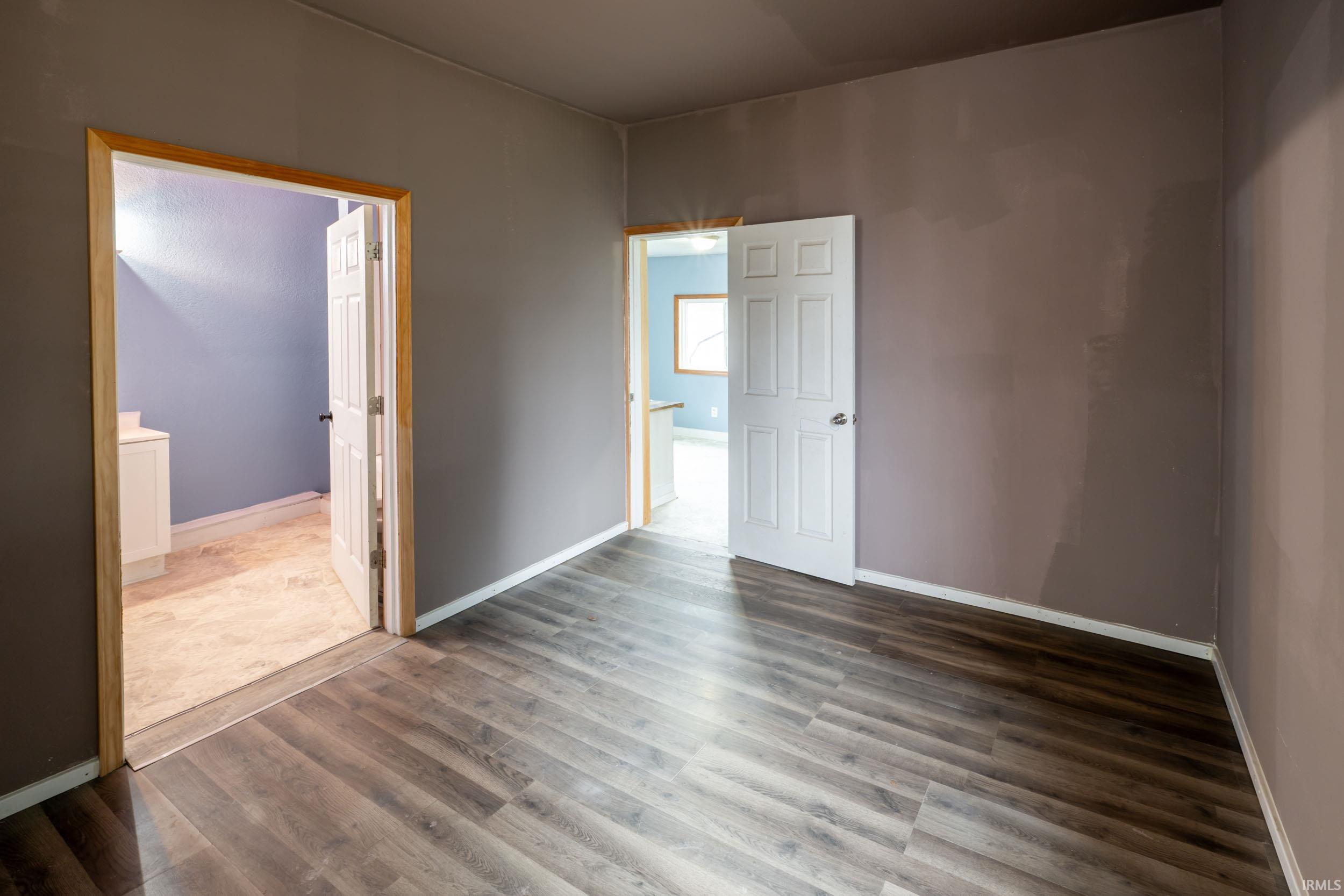 Empty room featuring baseboards and dark wood finished floors
