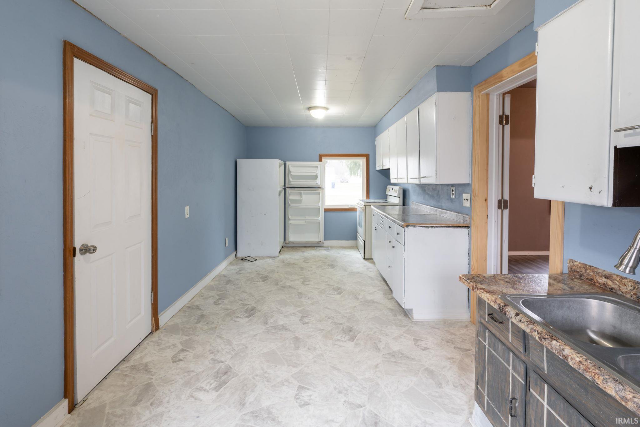 Kitchen with white cabinetry, white appliances, and dark countertops
