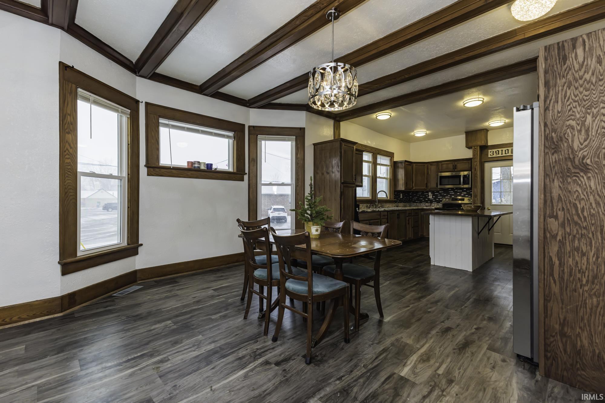 Dining area featuring beam ceiling, dark wood-type flooring, and a chandelier