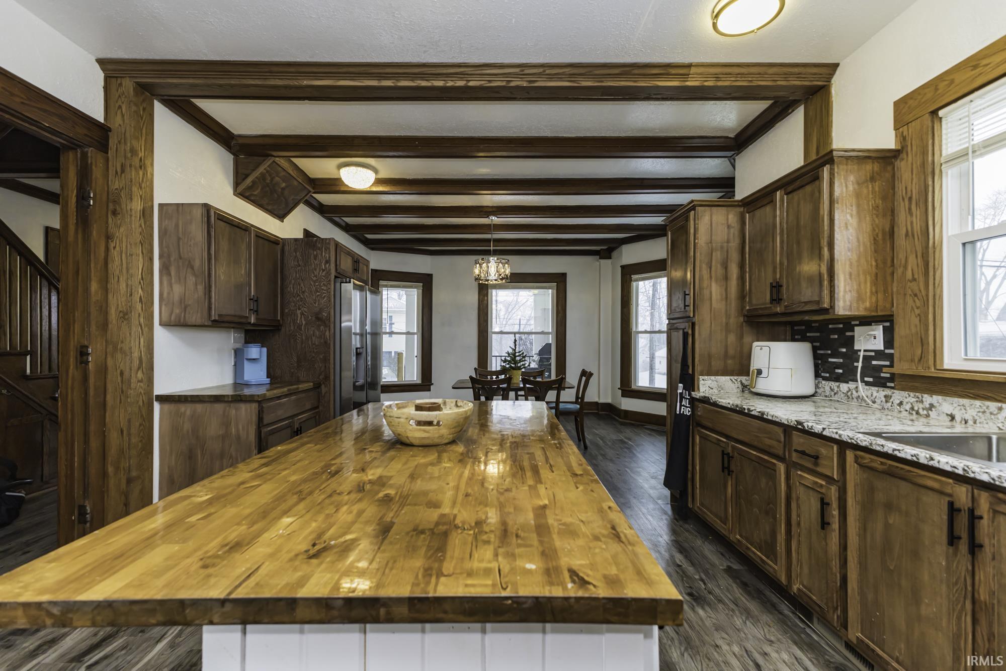 Kitchen featuring wooden counters, plenty of natural light, a center island, beamed ceiling, and stainless steel refrigerator with ice dispenser