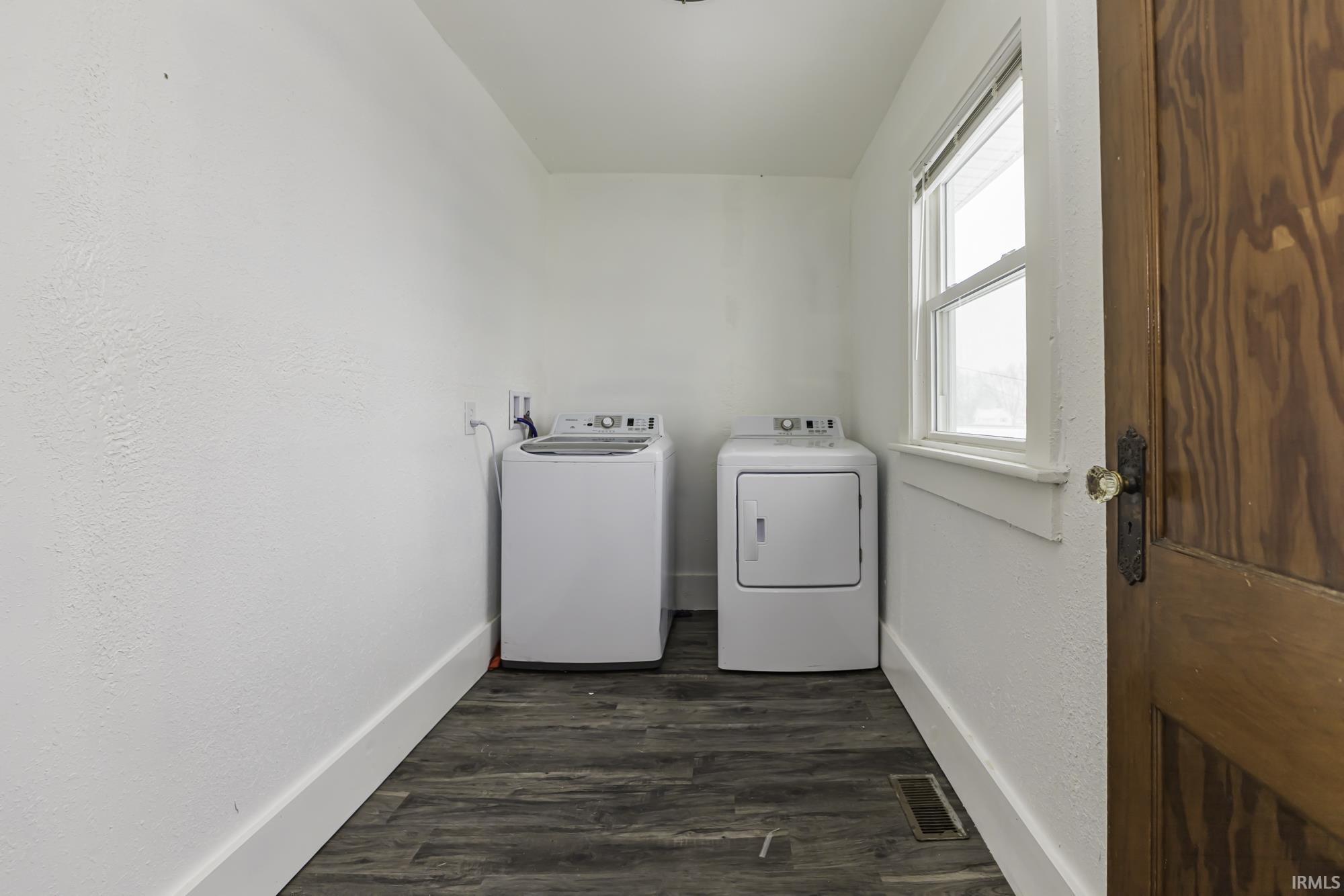 Washroom featuring dark wood-type flooring and washer and clothes dryer