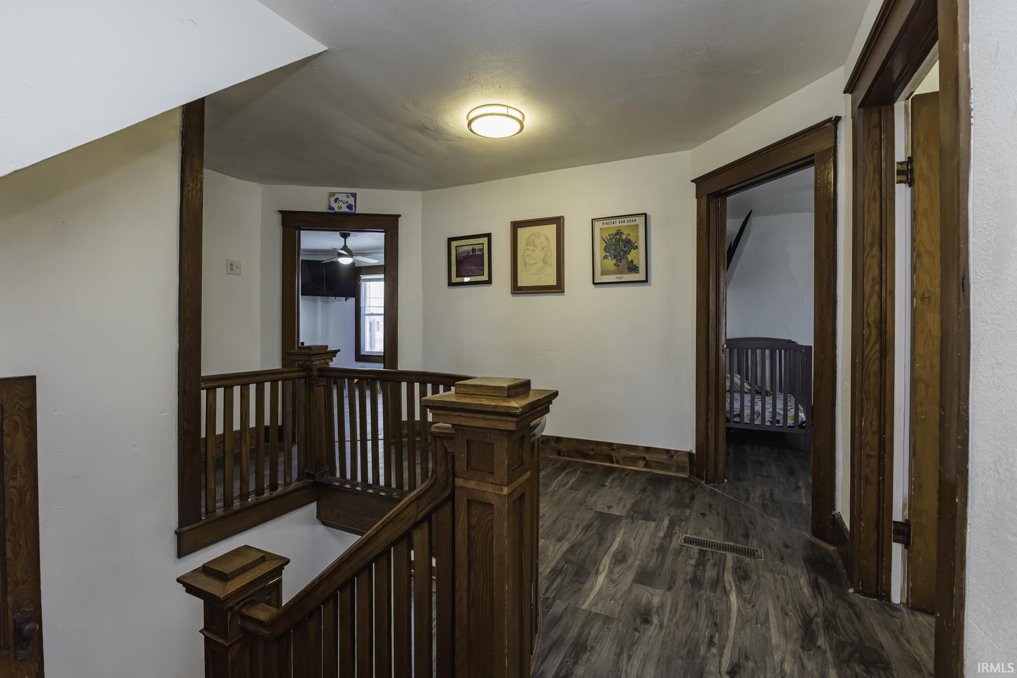 Hall featuring an upstairs landing and dark wood-style floors