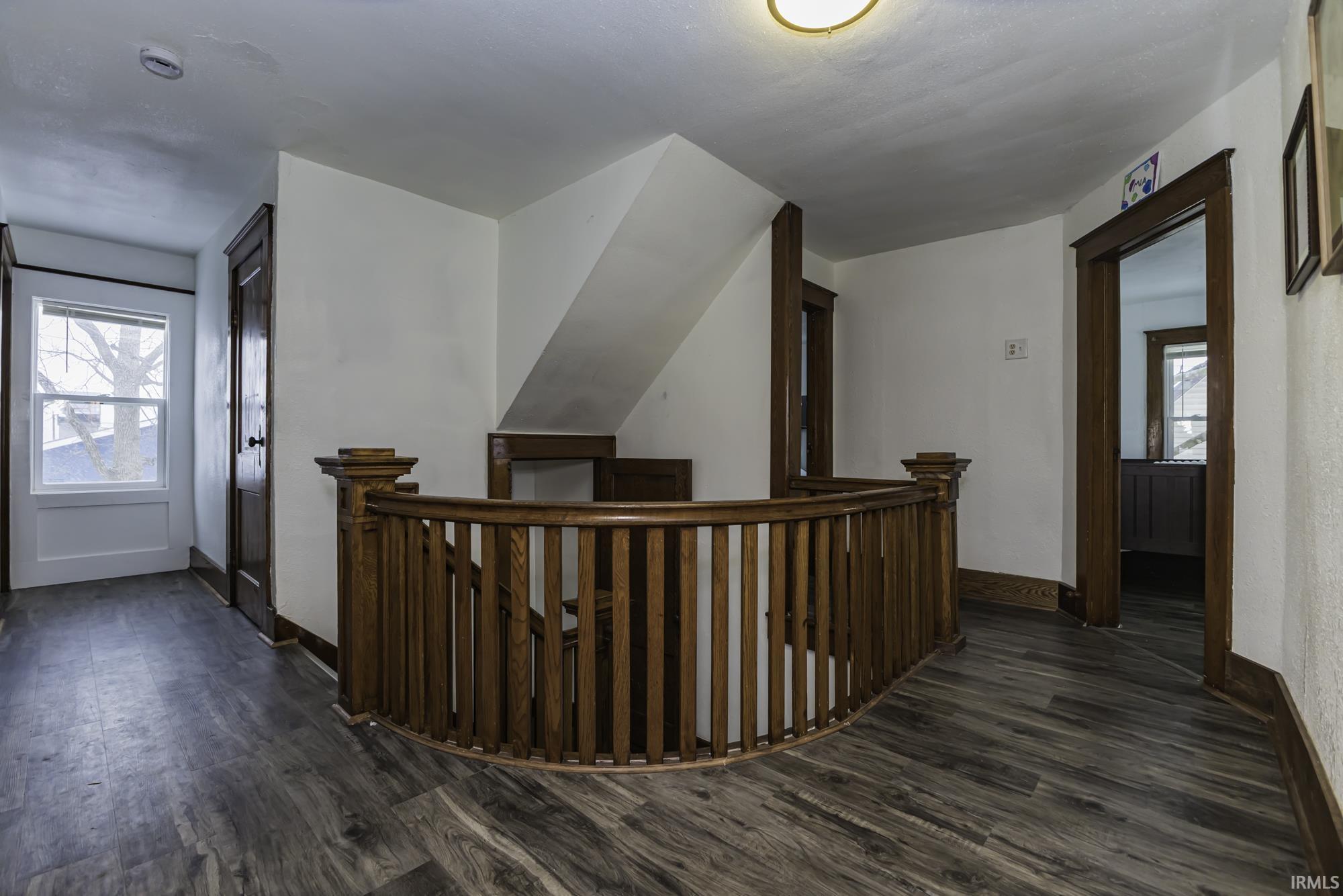 Corridor featuring an upstairs landing and dark wood finished floors