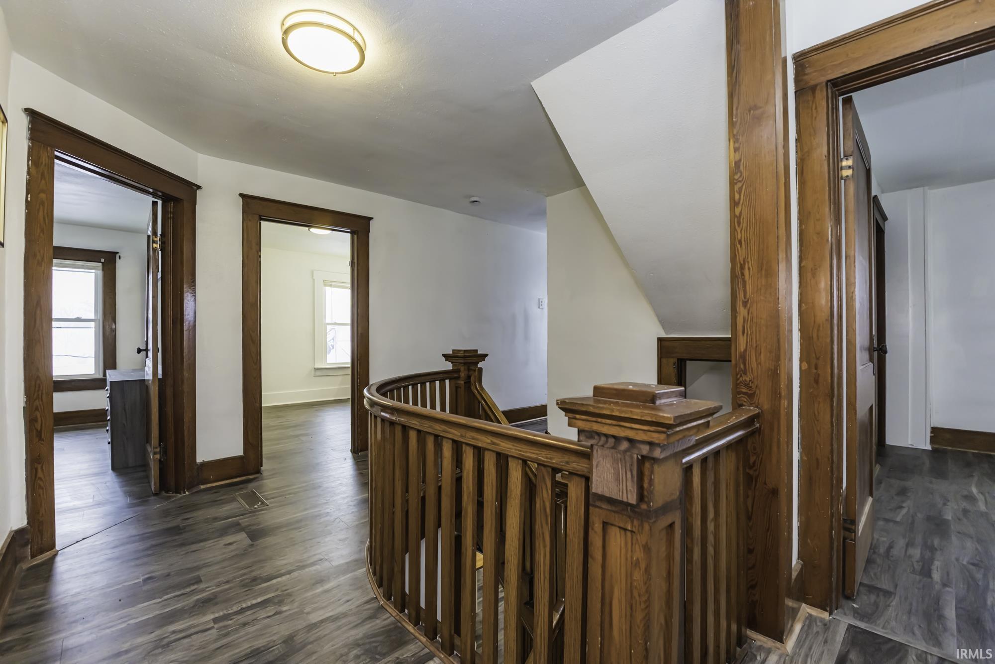 Corridor featuring an upstairs landing and dark wood-style floors